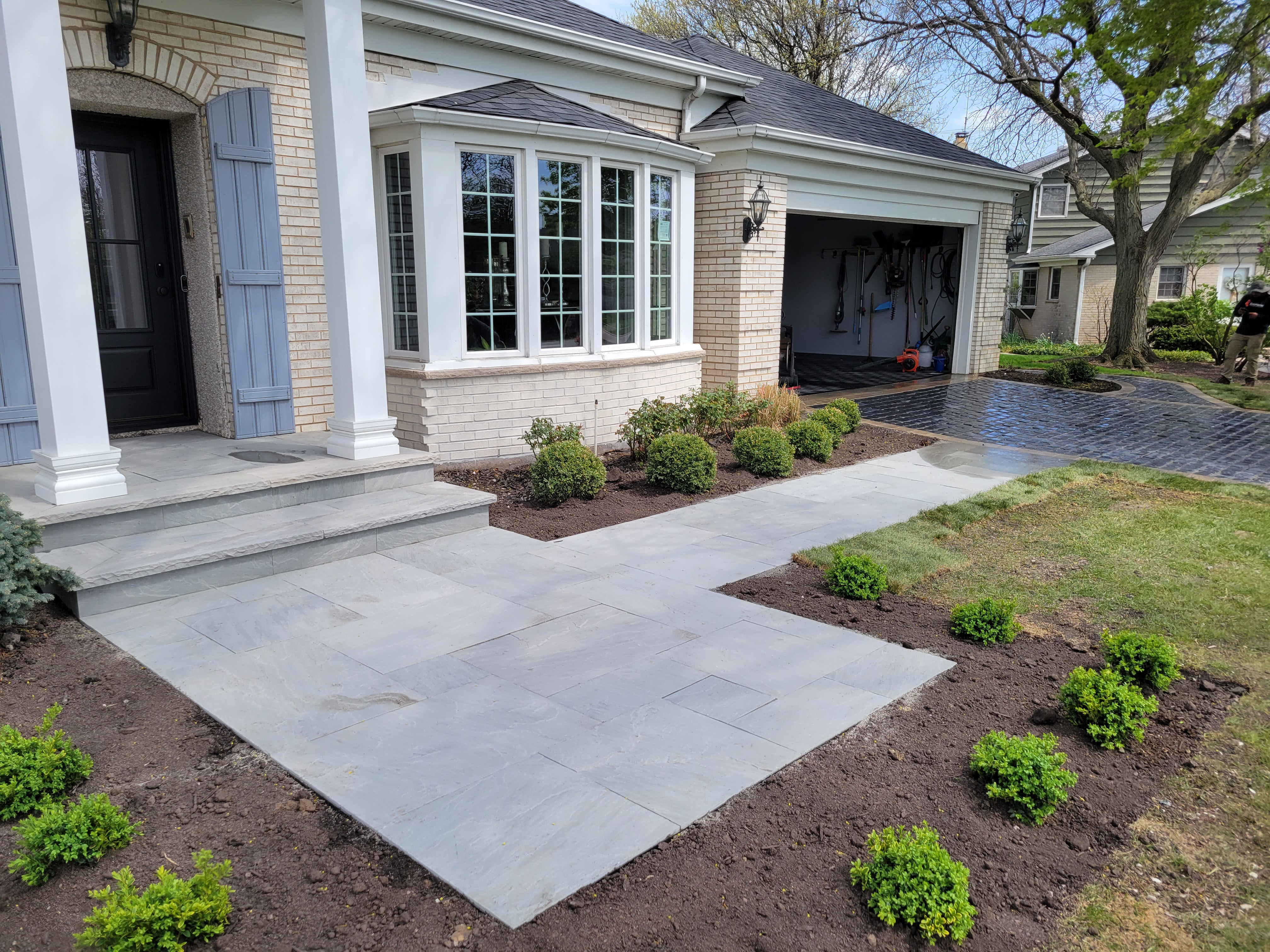 Newly paved walkway and landscaping in front of a brick house
