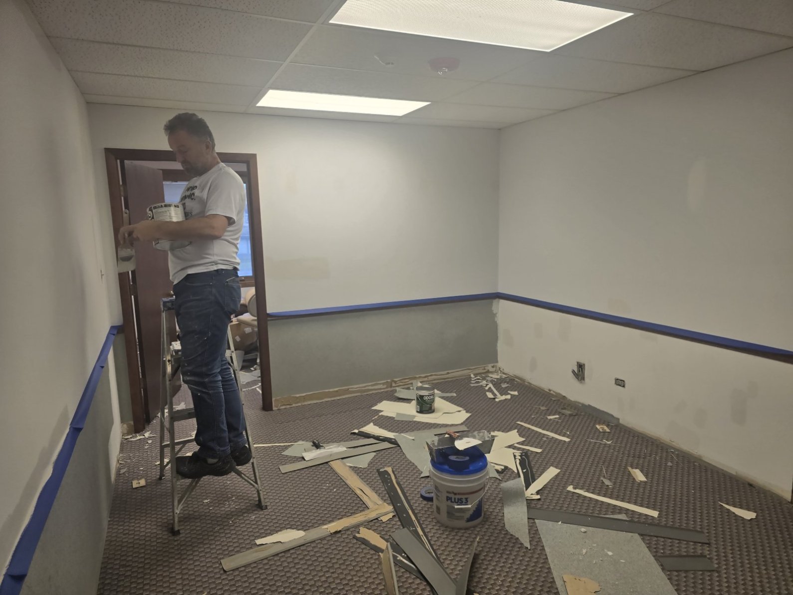 A person is painting a room that is undergoing renovation.