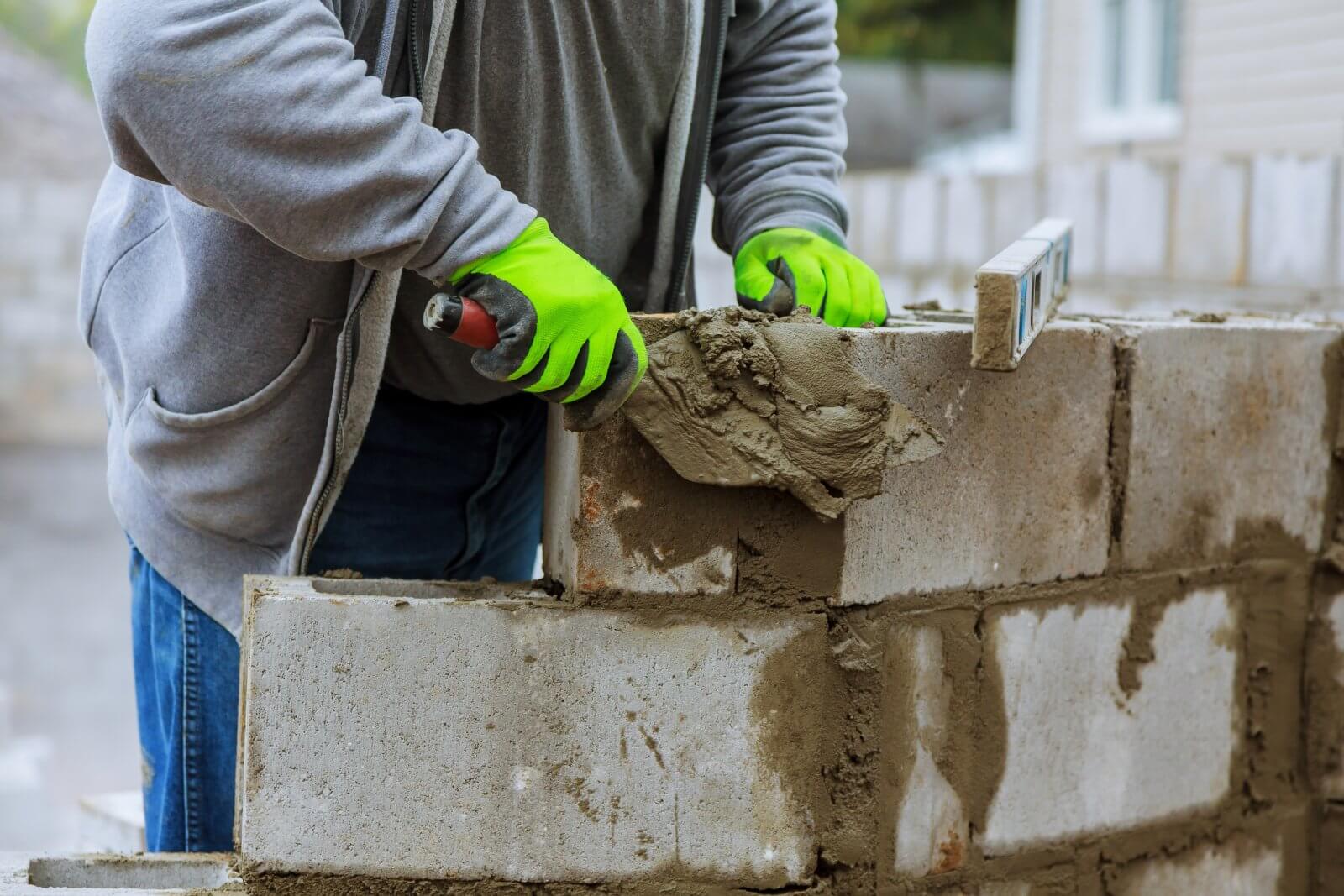 A person is laying a concrete block on a wall