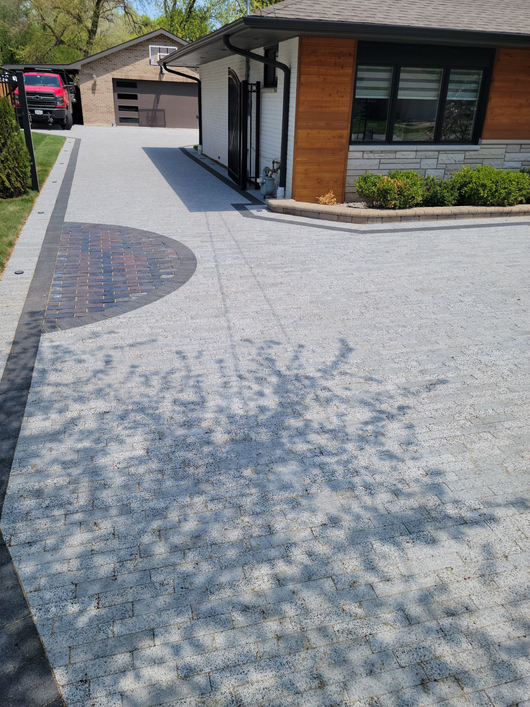 Modern driveway with brick accents and a red truck.