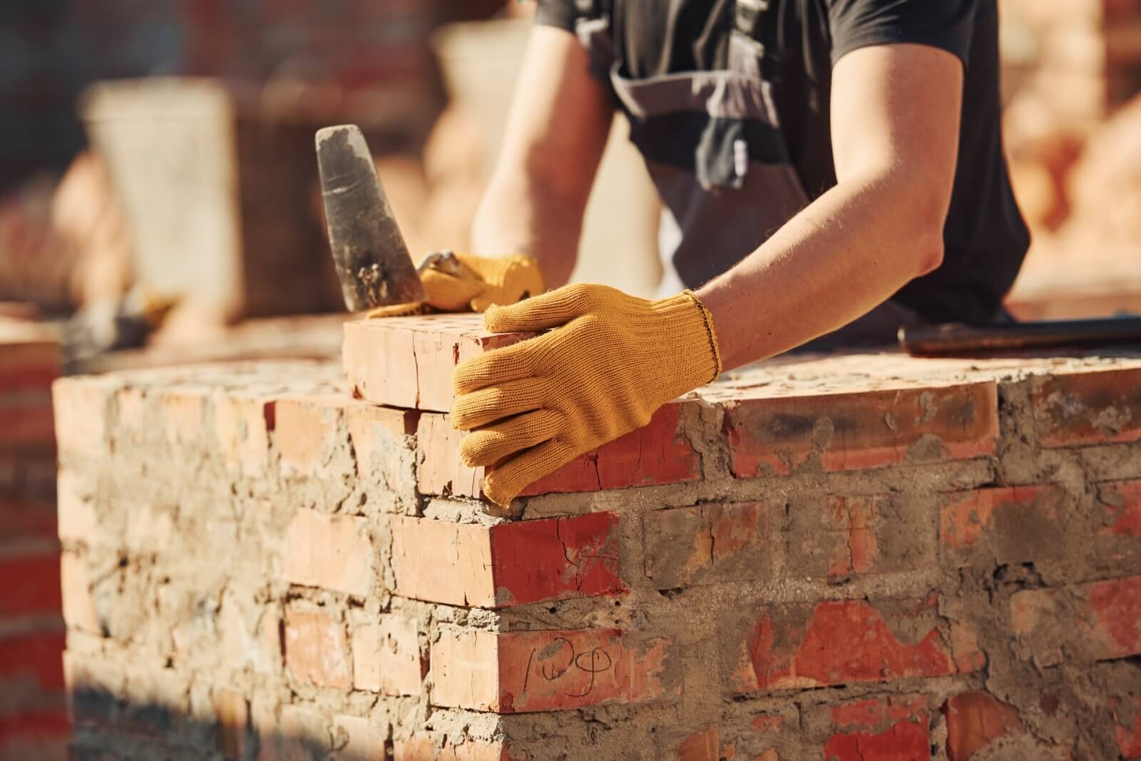 A person is building a brick wall with a trowel and mortar