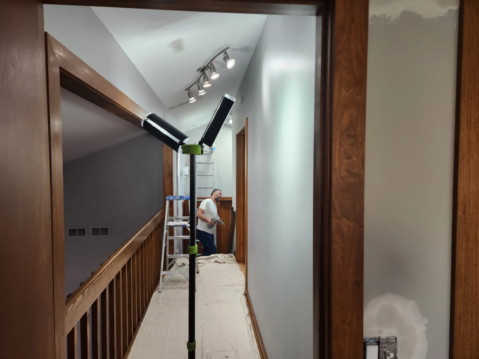 A person is painting a hallway with a ladder and lights