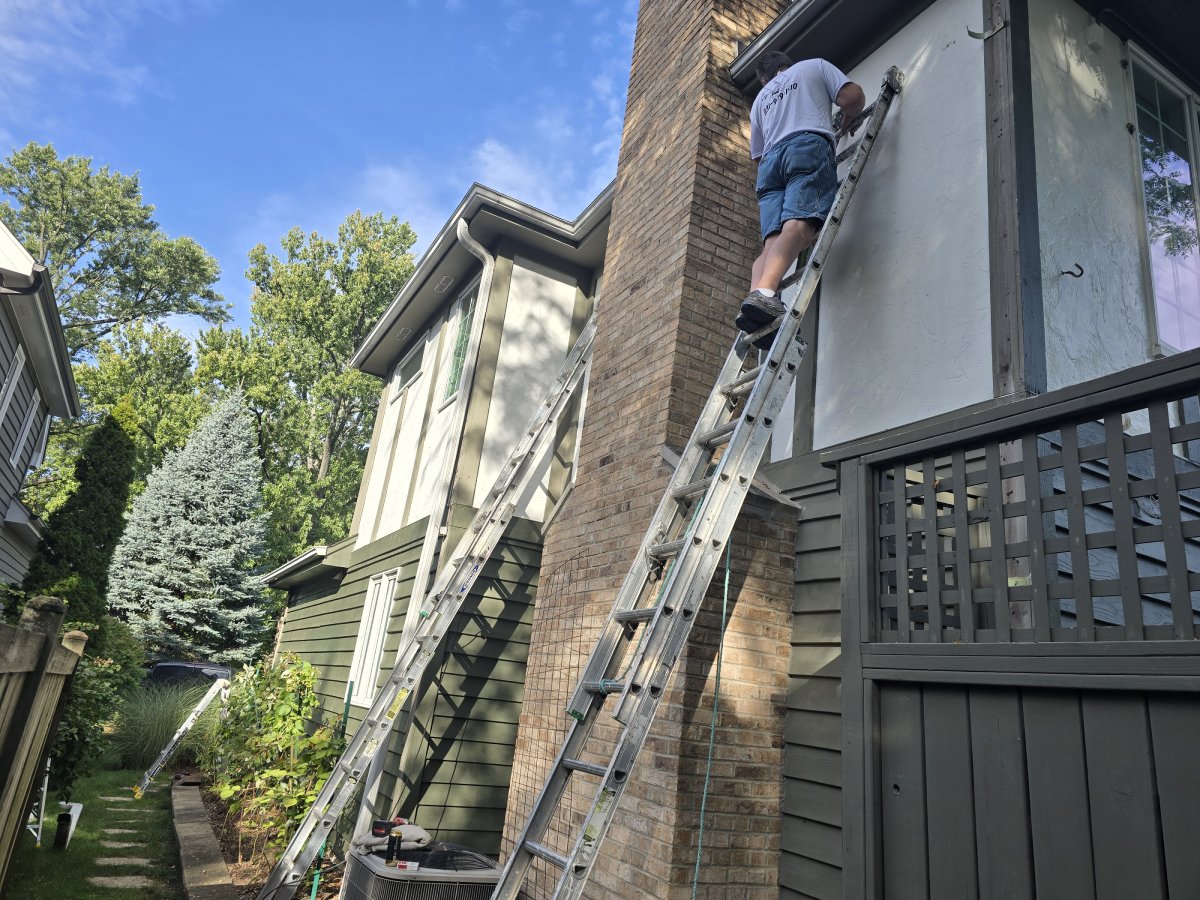 Professional painting contractor using a ladder for exterior work