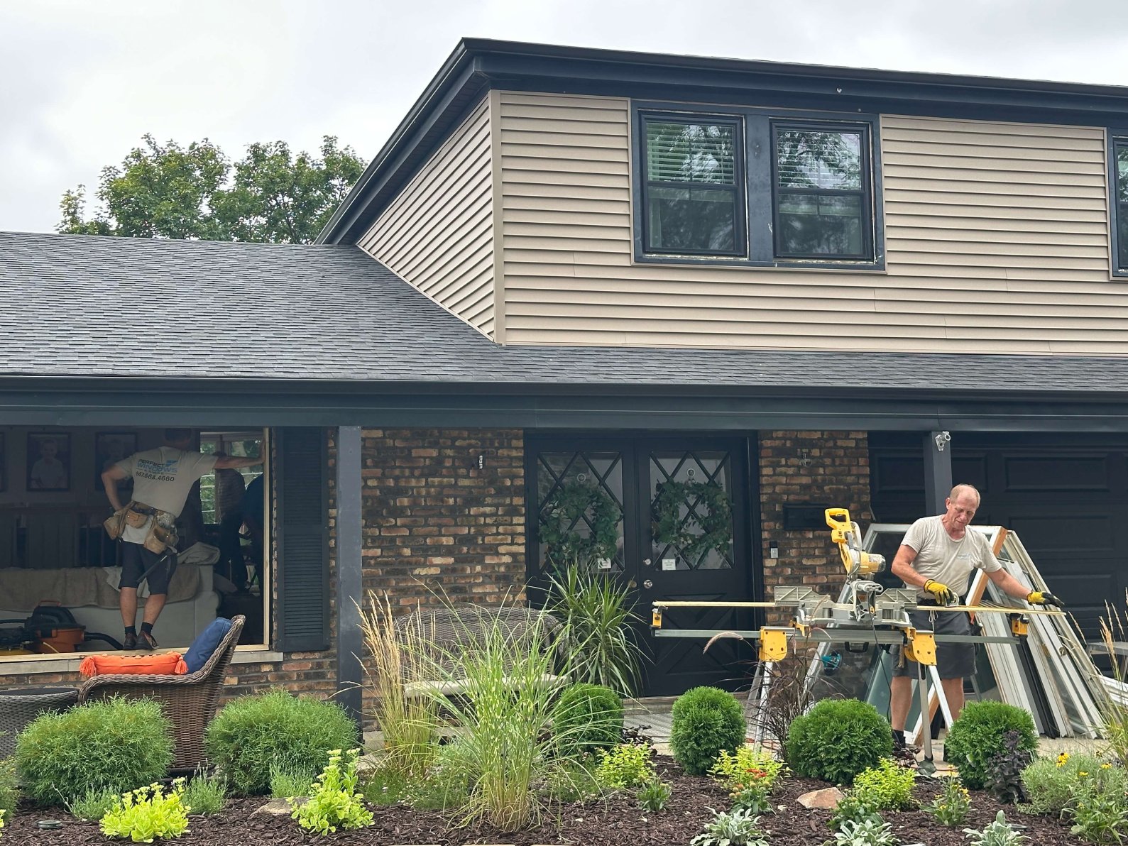 Workers installing new windows on a house exterior