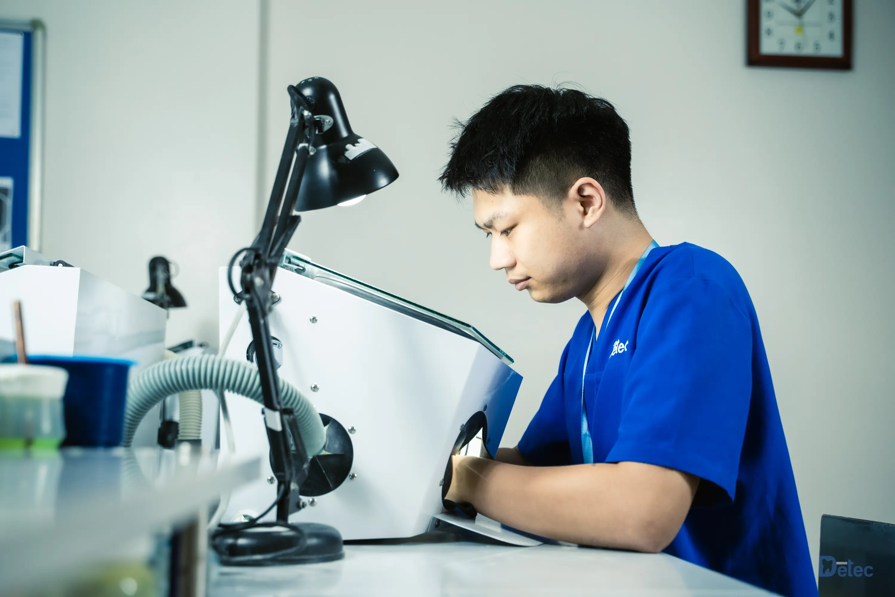 A dental technician working under bright light