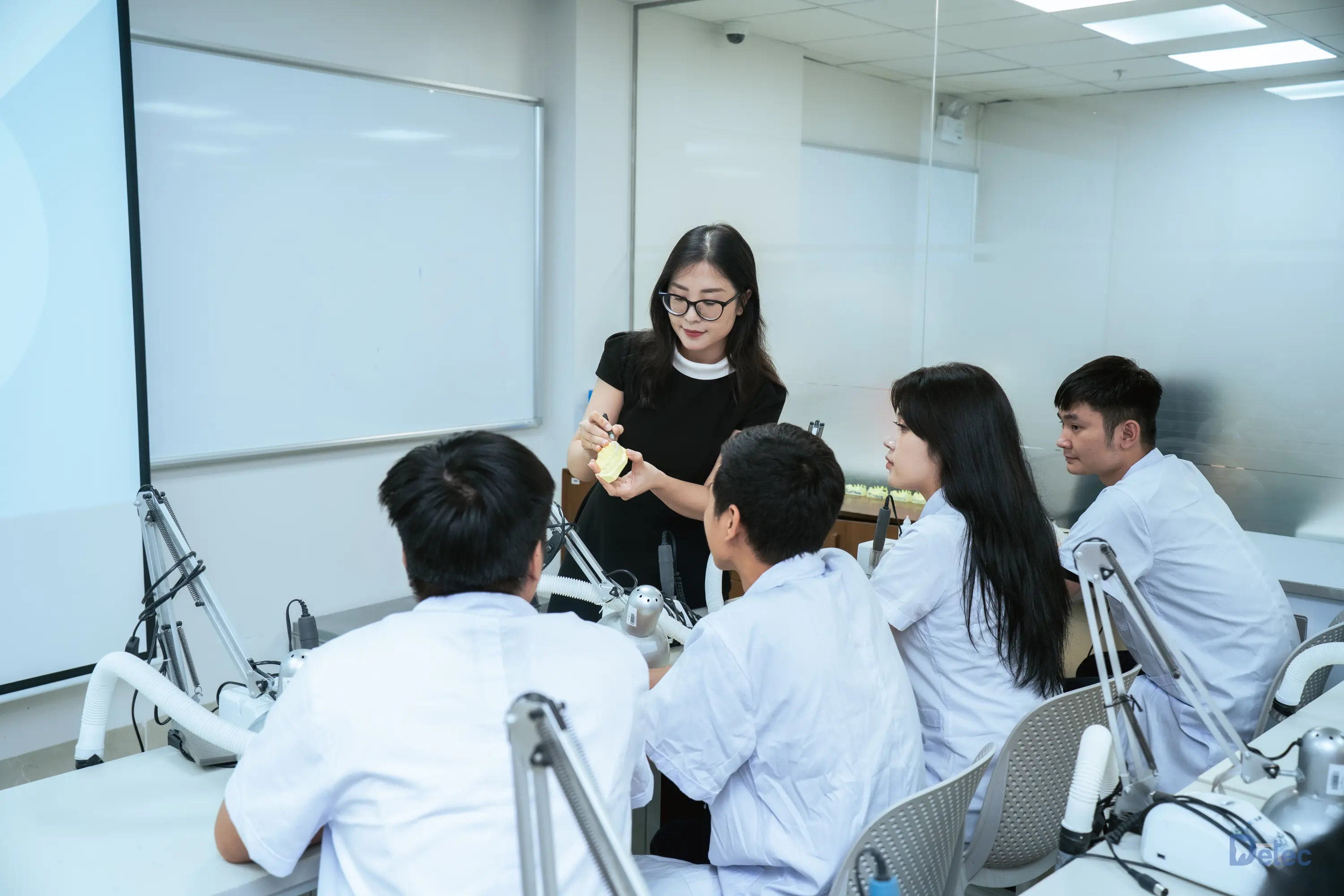 Technicians observing professional digital dental manufacturing tasks at a workbench