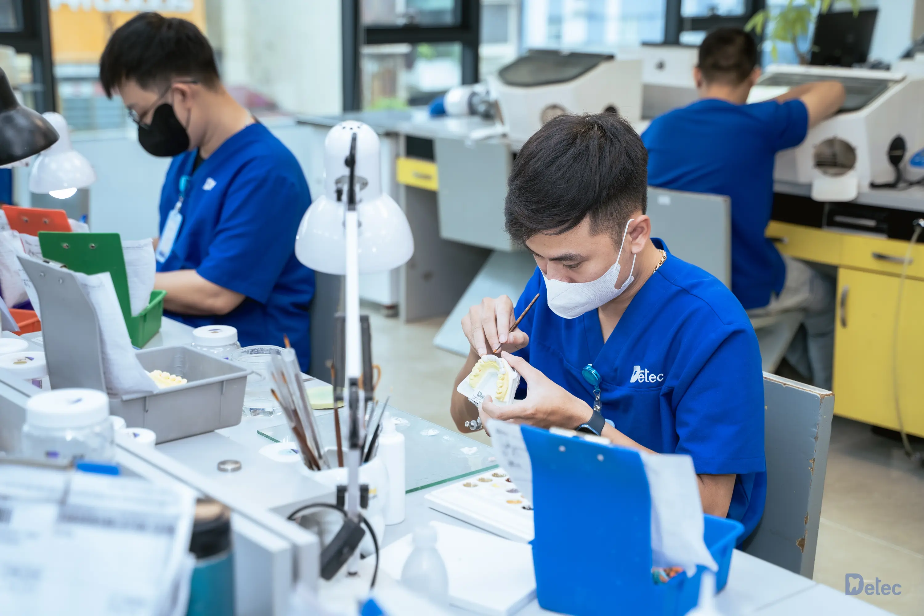 Workers in blue scrubs crafting prosthetics