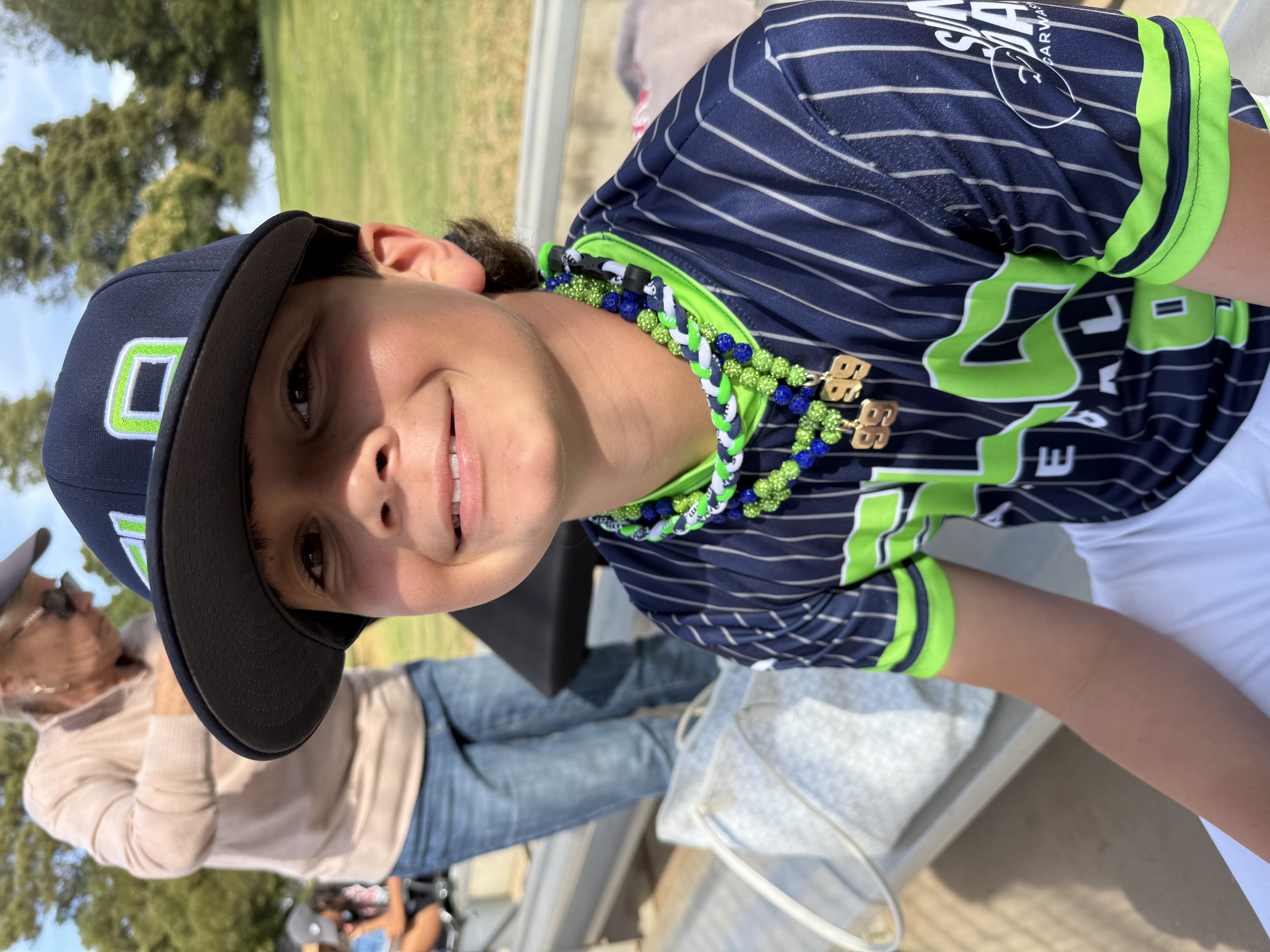 Young baseball player in uniform smiles with beads