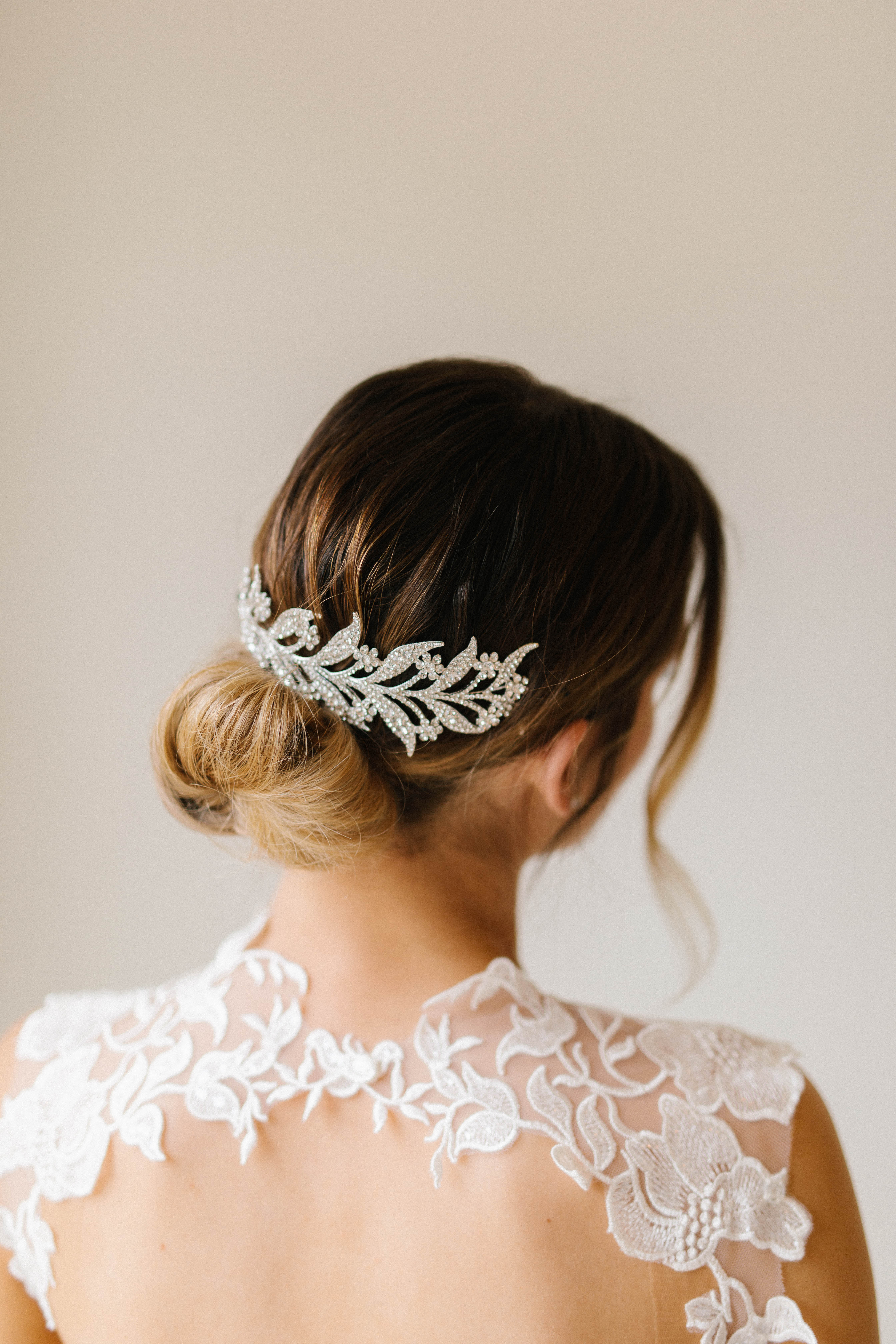 A person wears a white lace dress and a sparkling hair accessory.