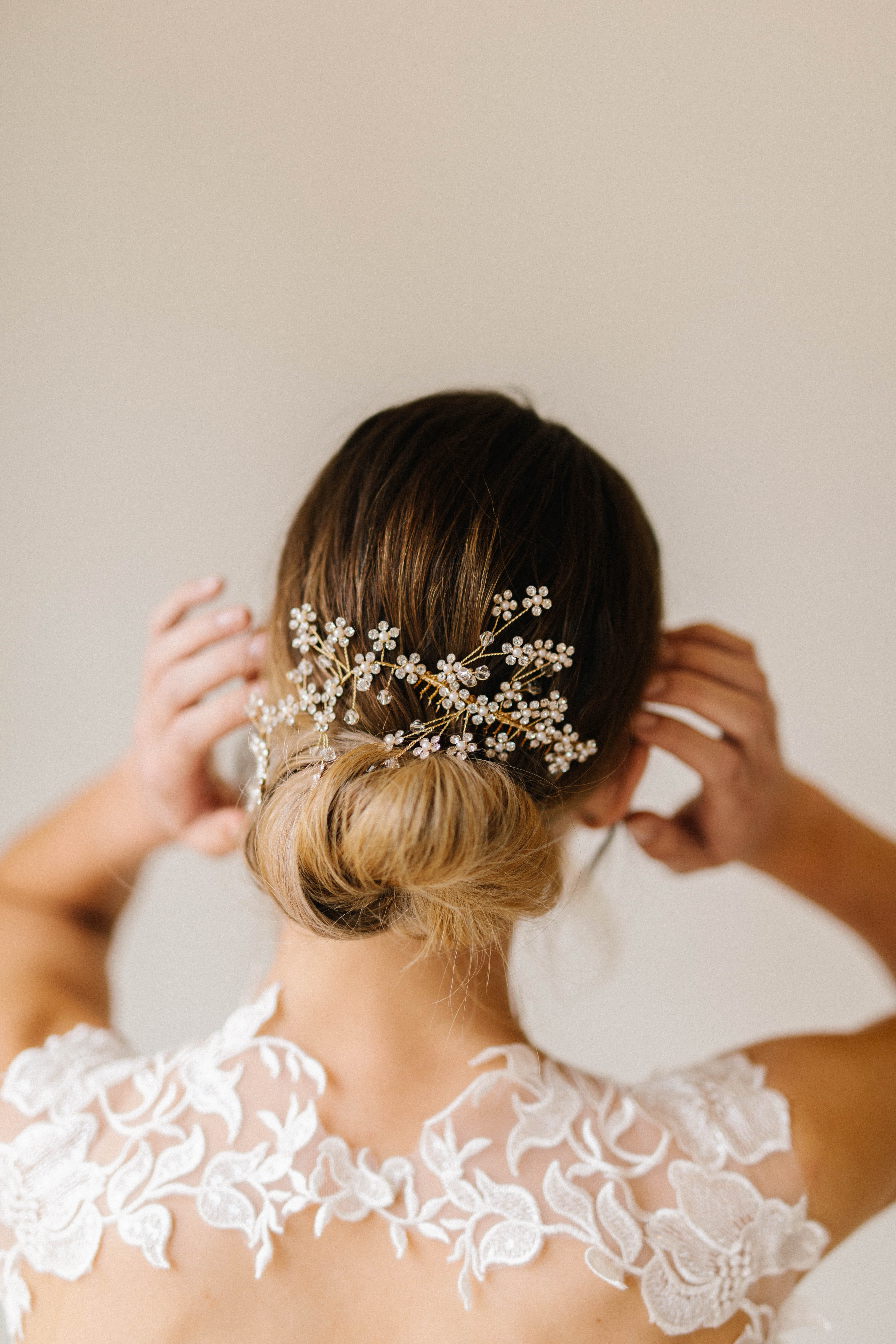 A person's hair is styled in a bun with a delicate floral hairpiece.