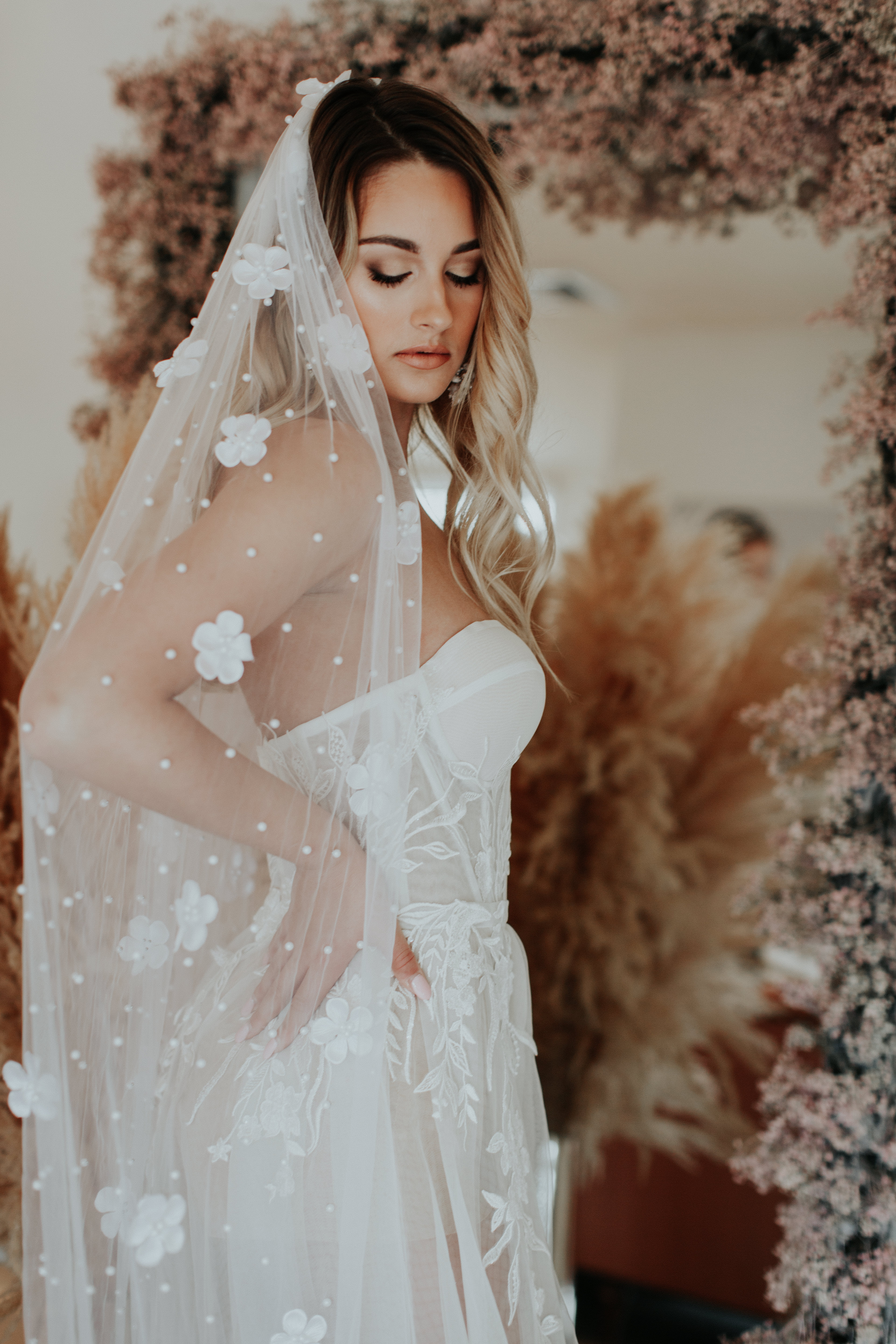 A person in a white wedding dress with a floral veil.