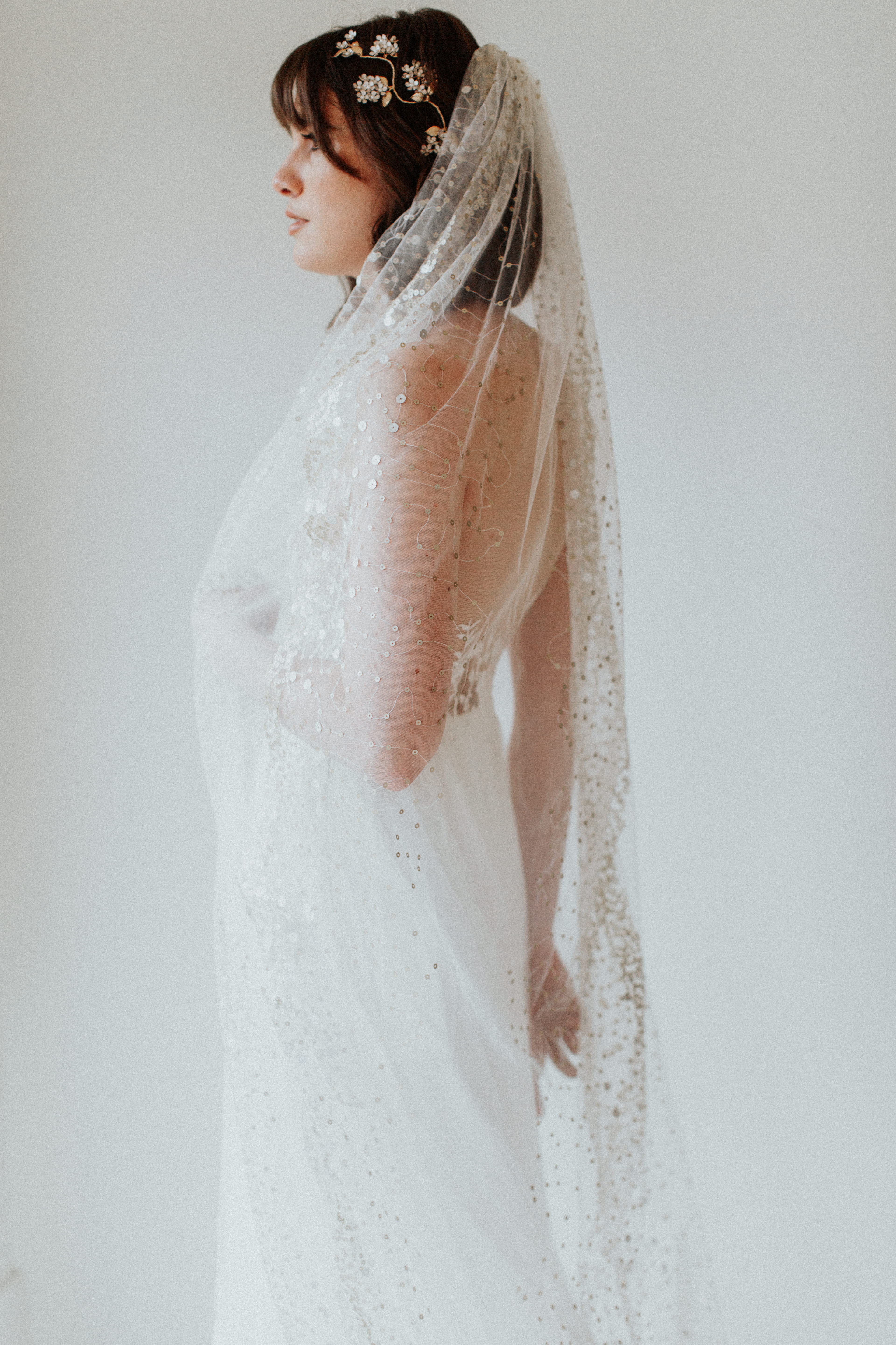 A person in a white dress with a veil and floral headpiece