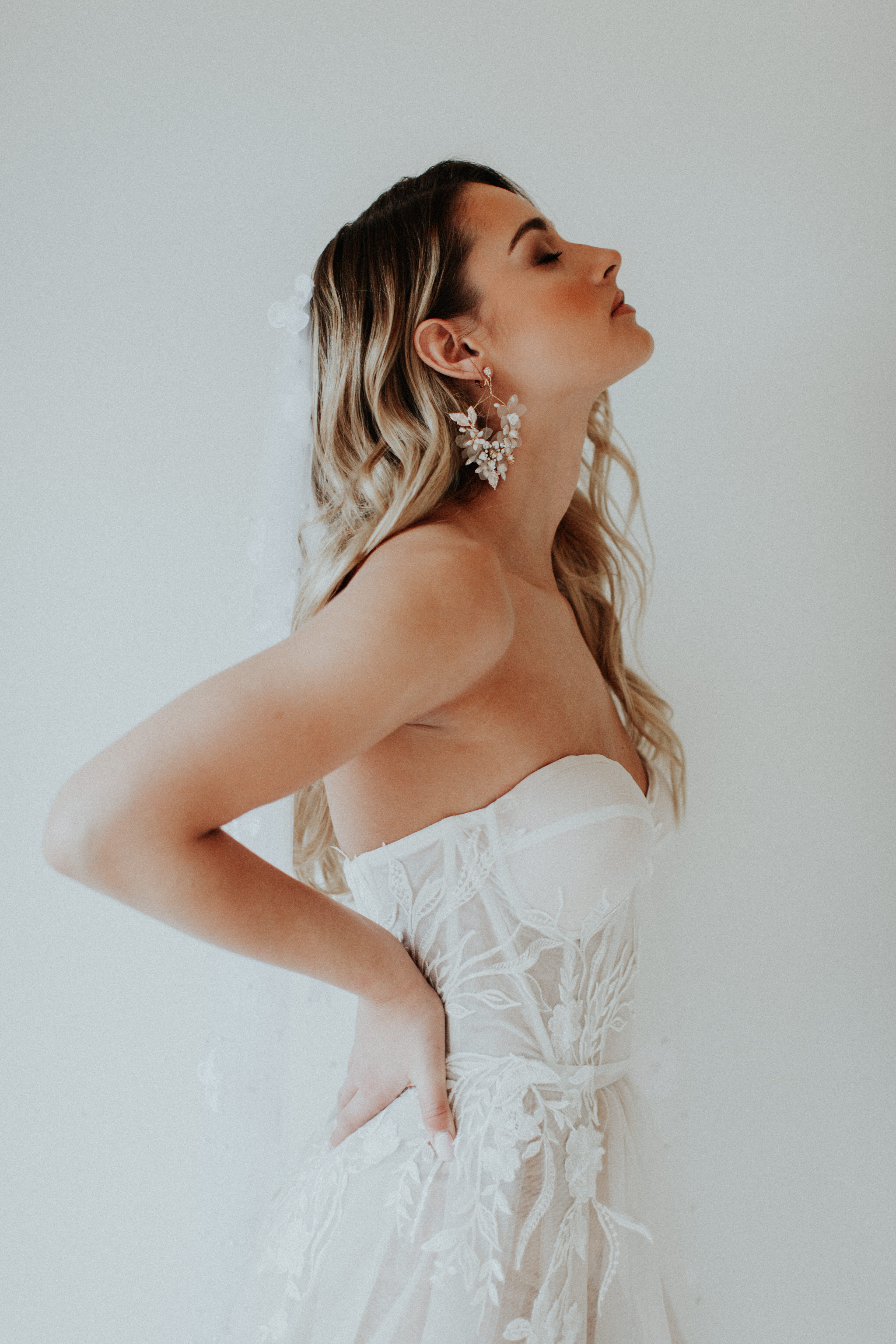 A person in a white wedding dress with a sparkling hair accessory.