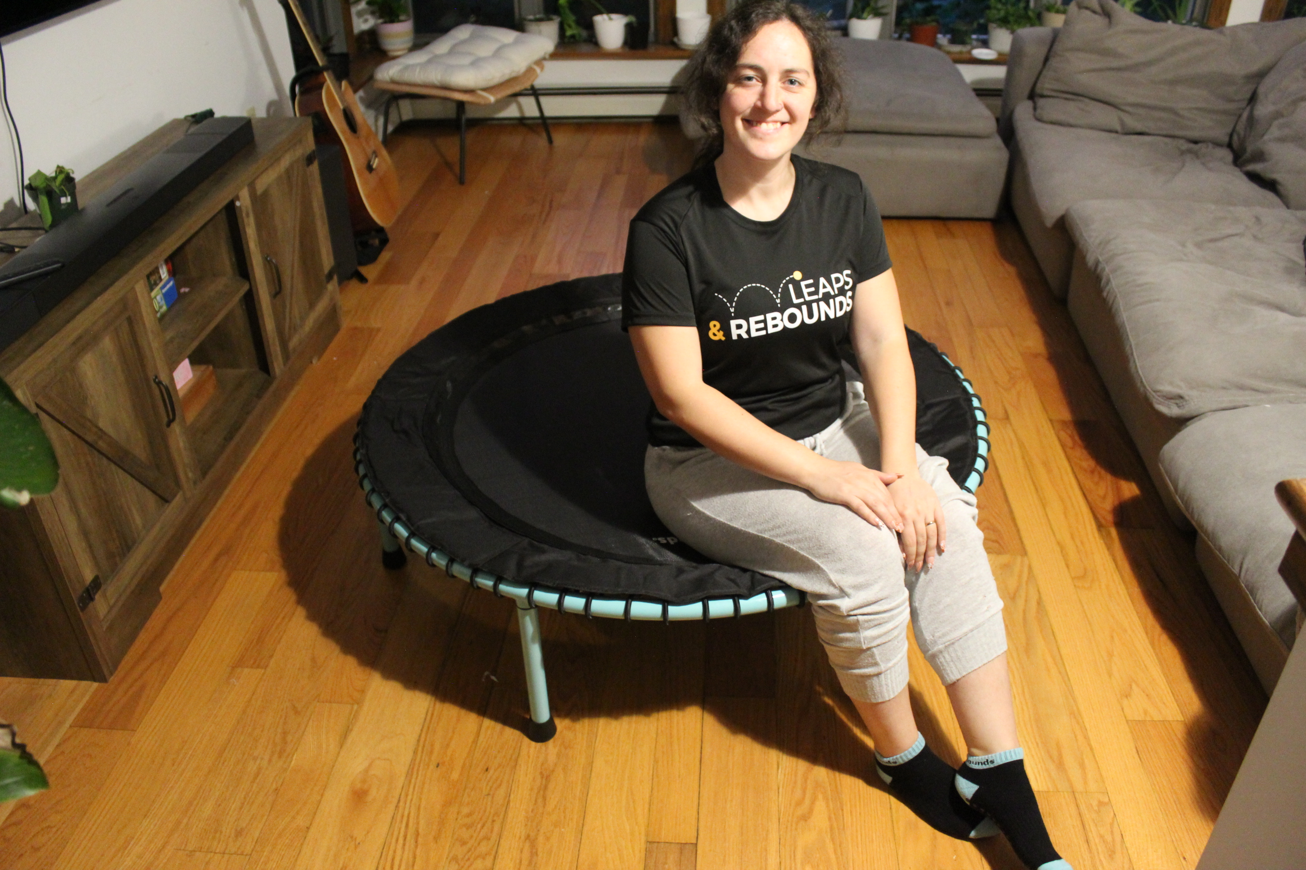 Person sitting on a mini trampoline in a cozy living room.