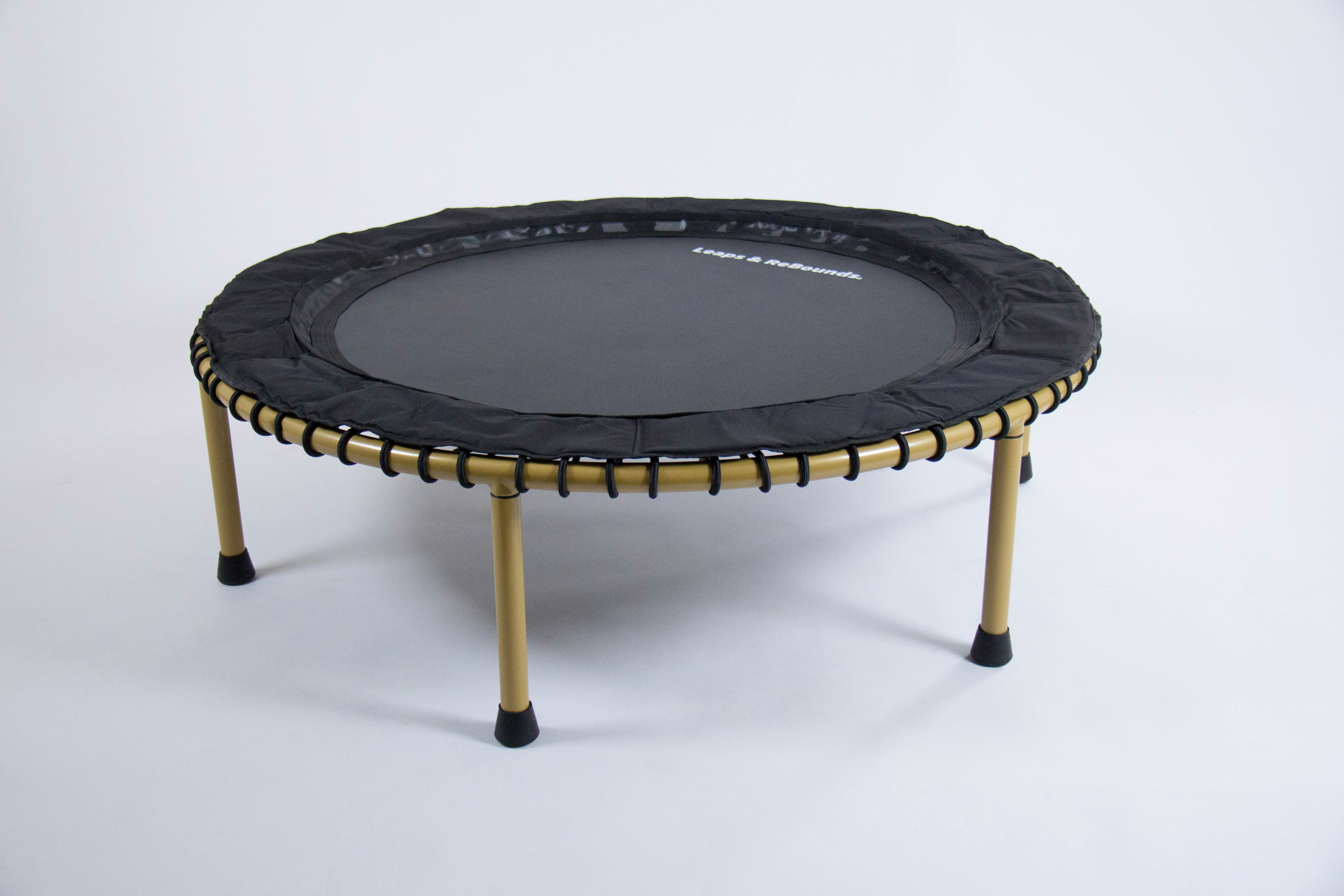 A small round trampoline with gold legs on white background