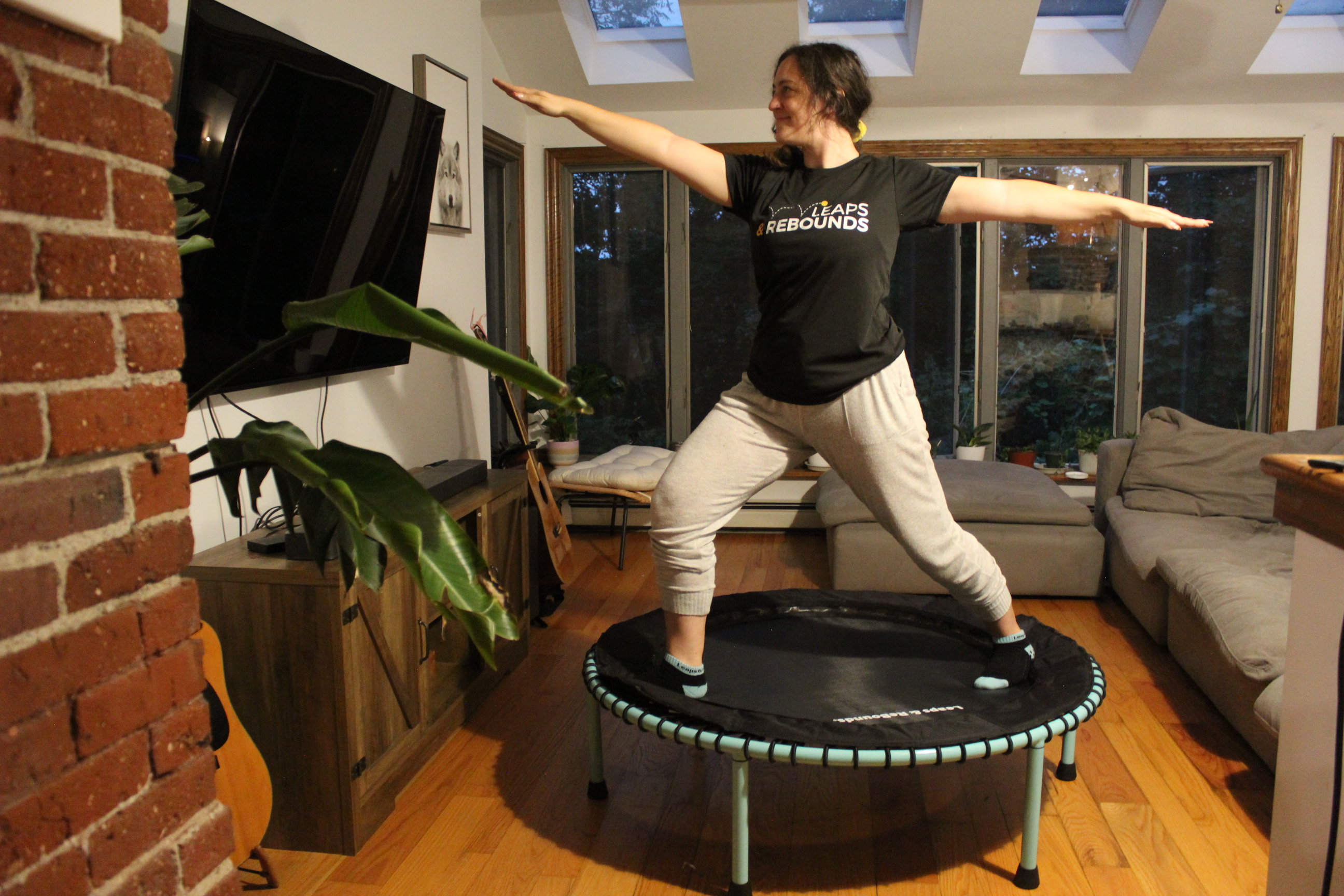 Person doing yoga pose on trampoline in cozy living room.