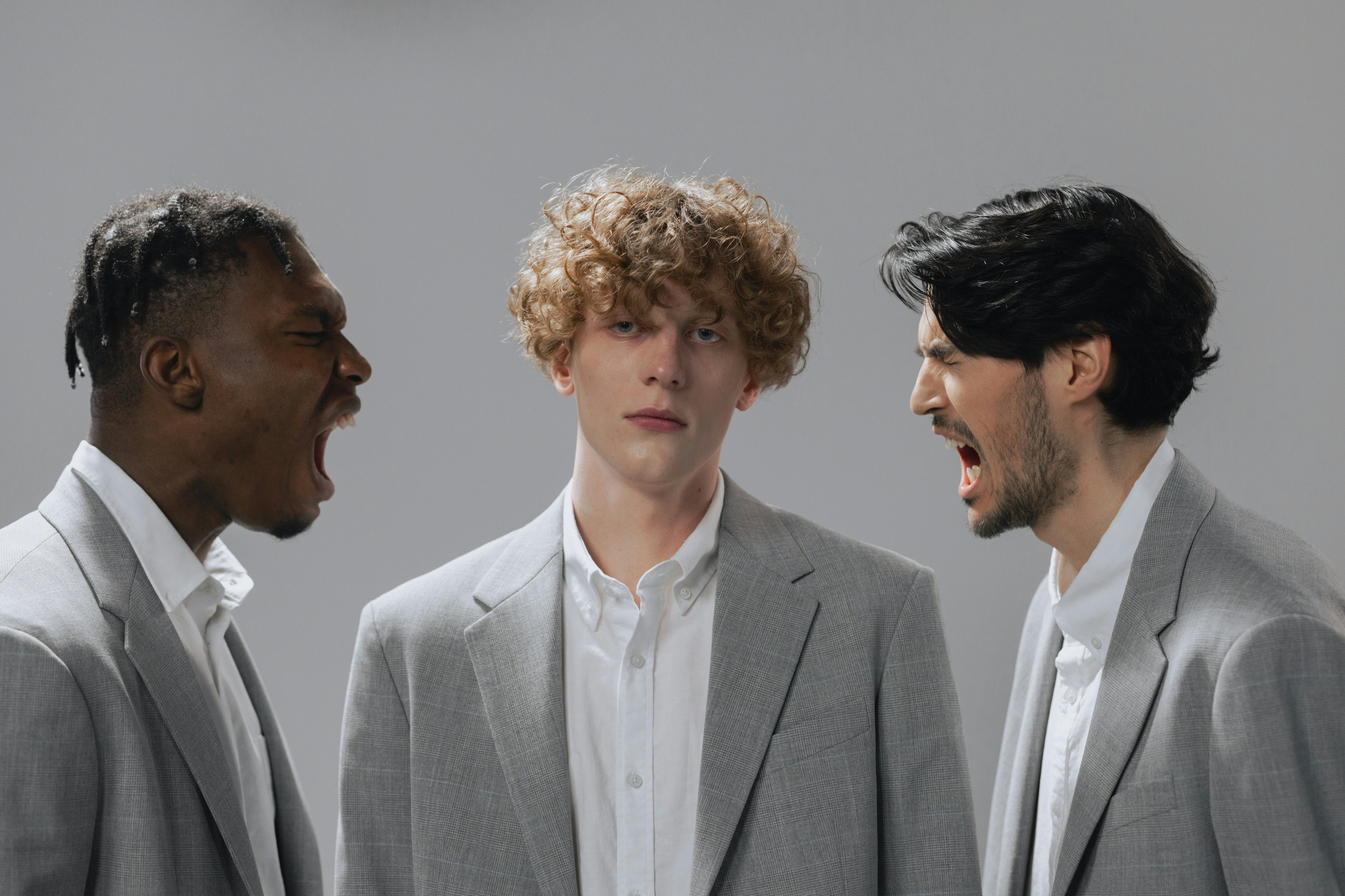 Three people in suits, two yelling at the middle person.