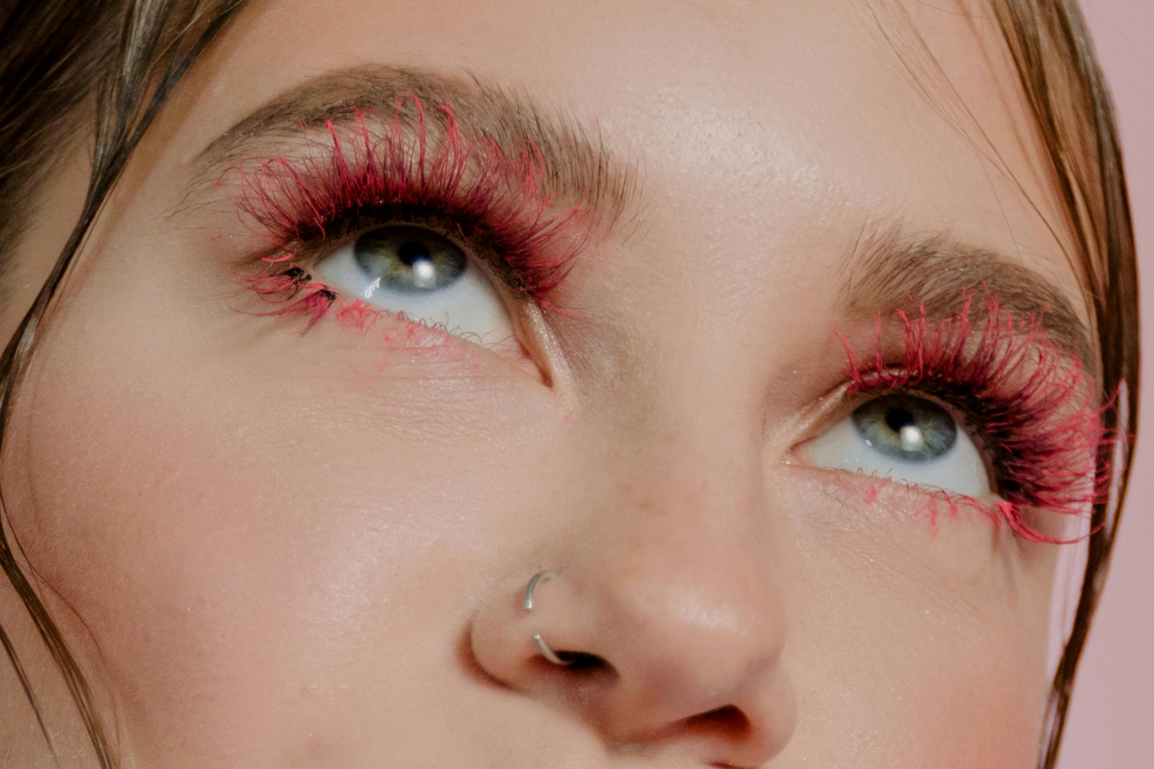 Close-up of eyes with dramatic pink eyelashes and nose ring.