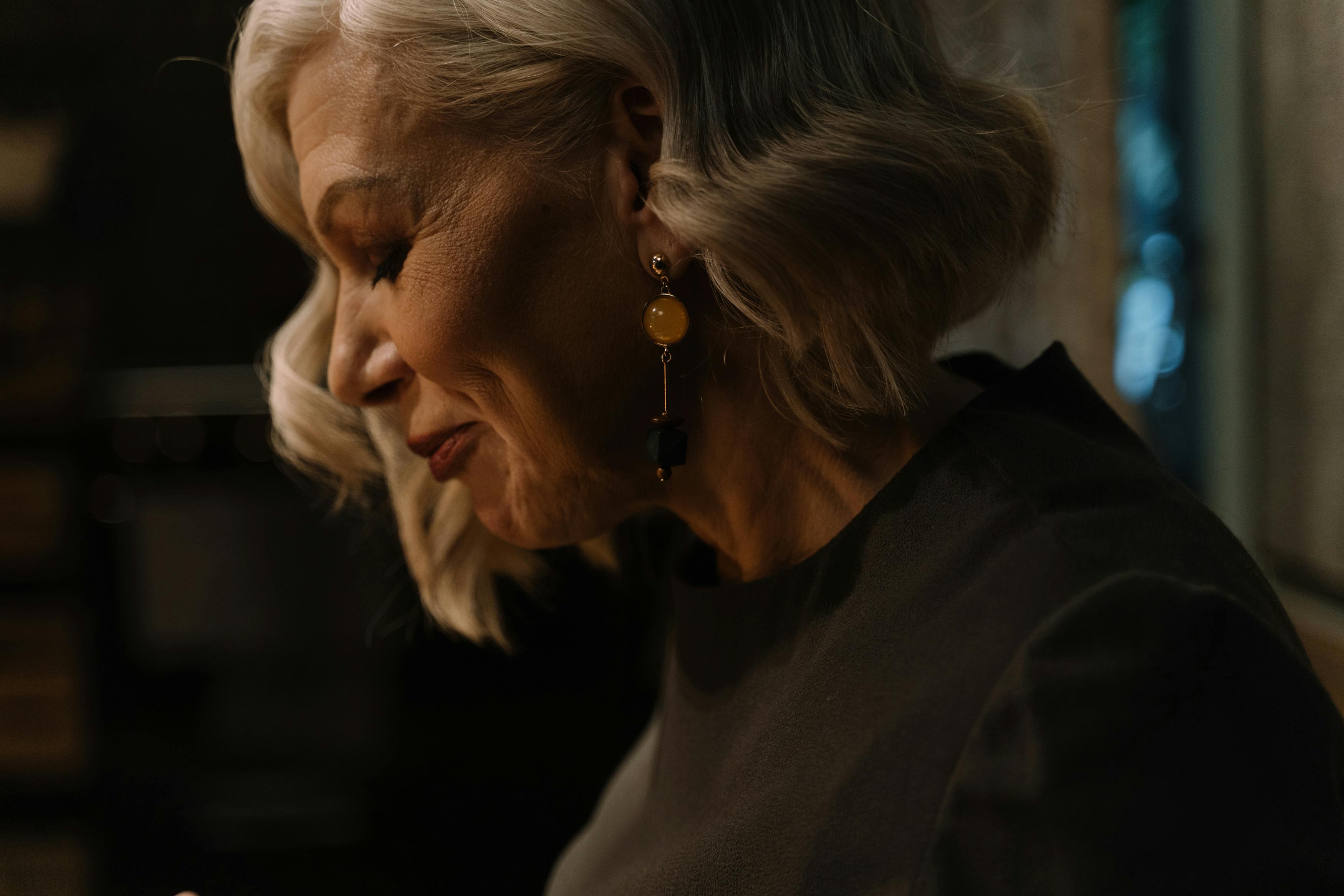 Person with short blonde hair and earrings in soft lighting.