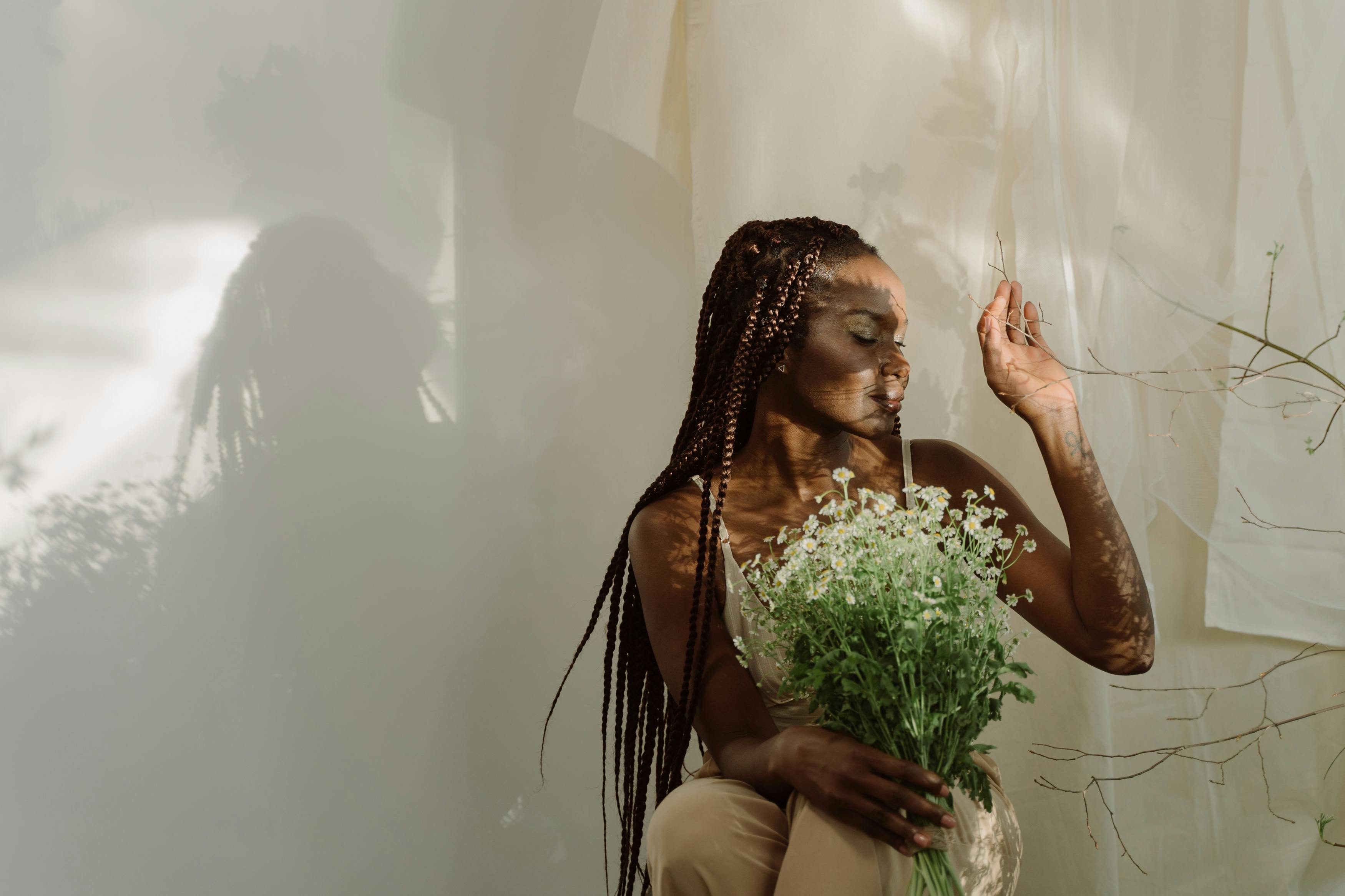 Person holding bouquet of flowers, surrounded by soft natural light.