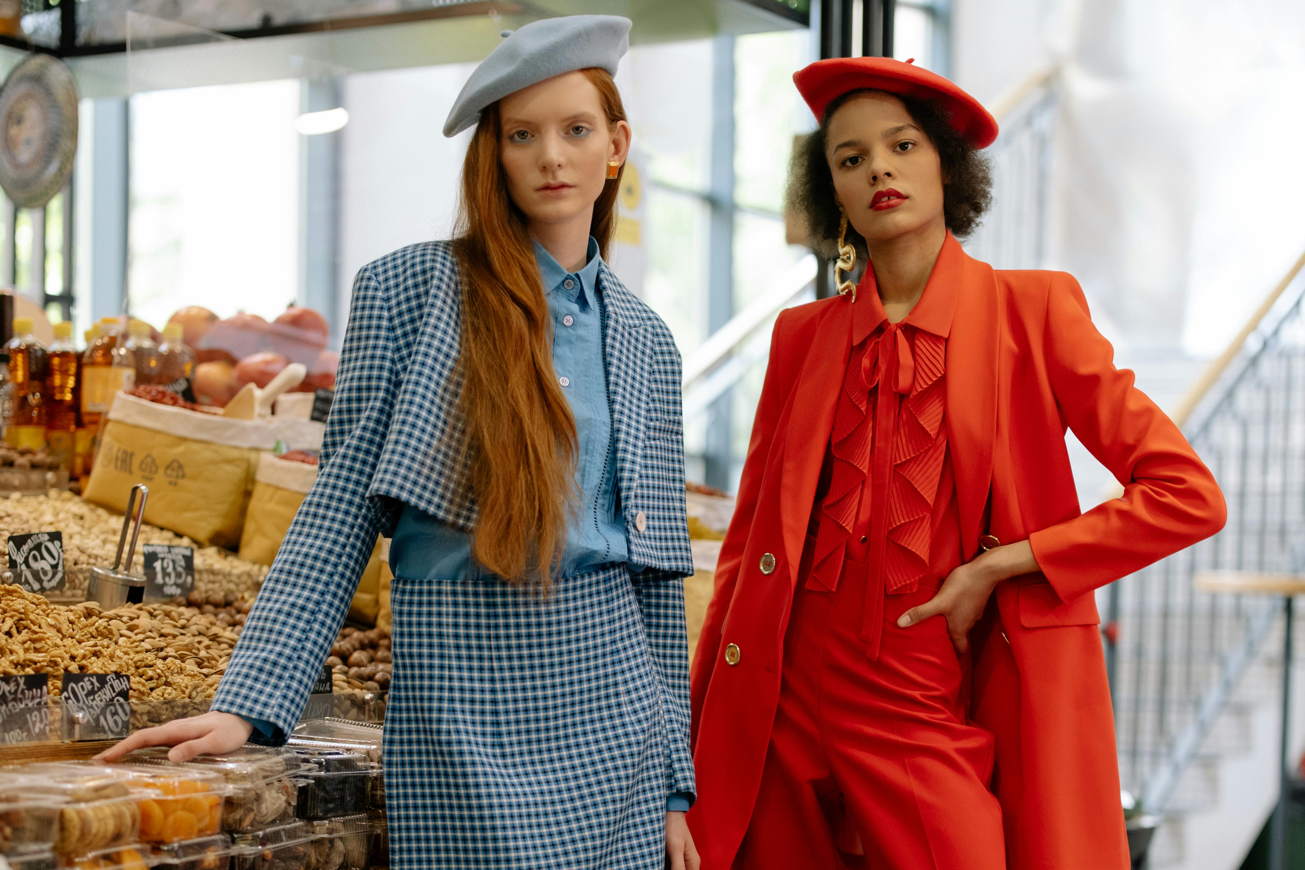 Two people in stylish outfits stand in a market stall.