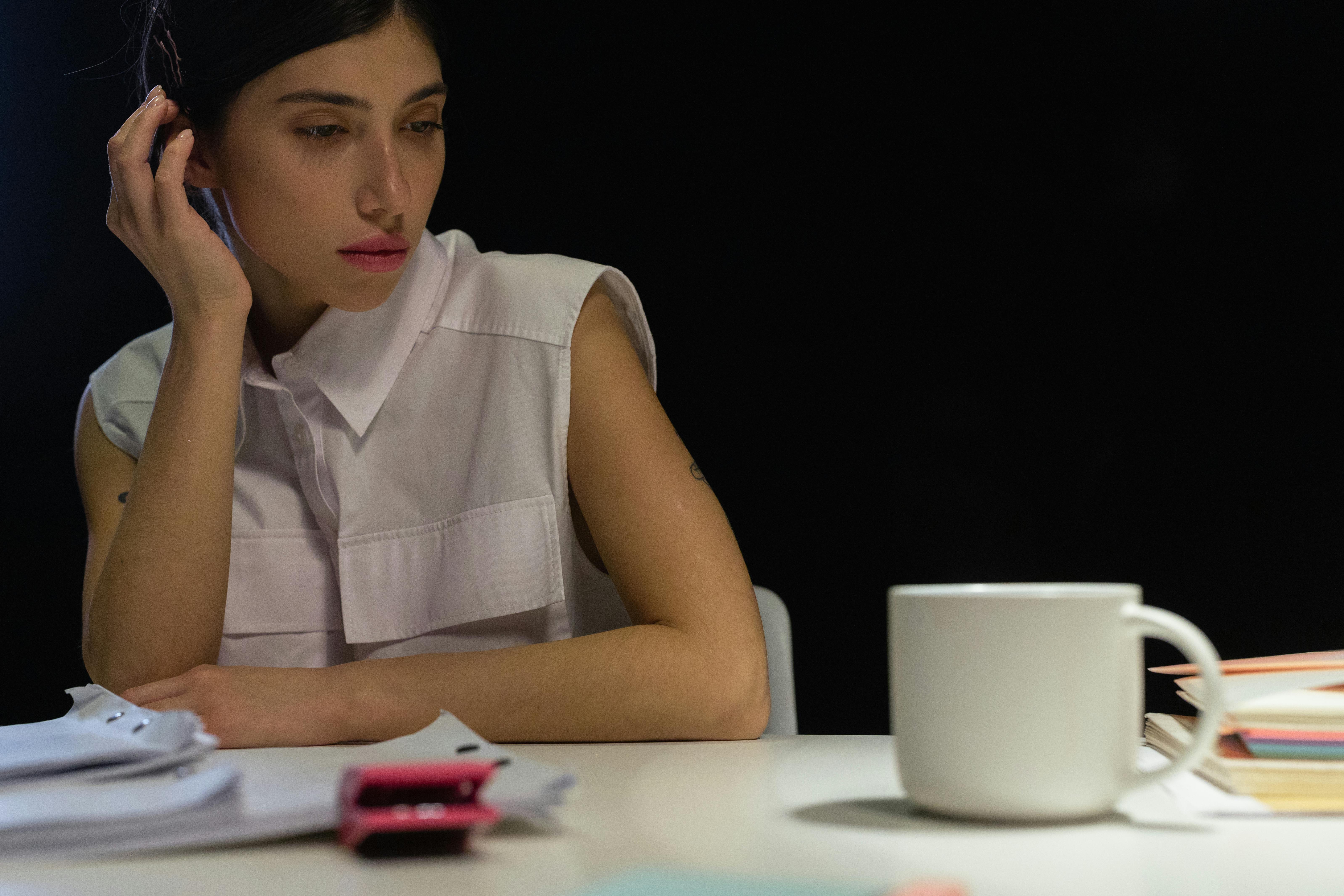 A person sits at a desk with papers and a mug.