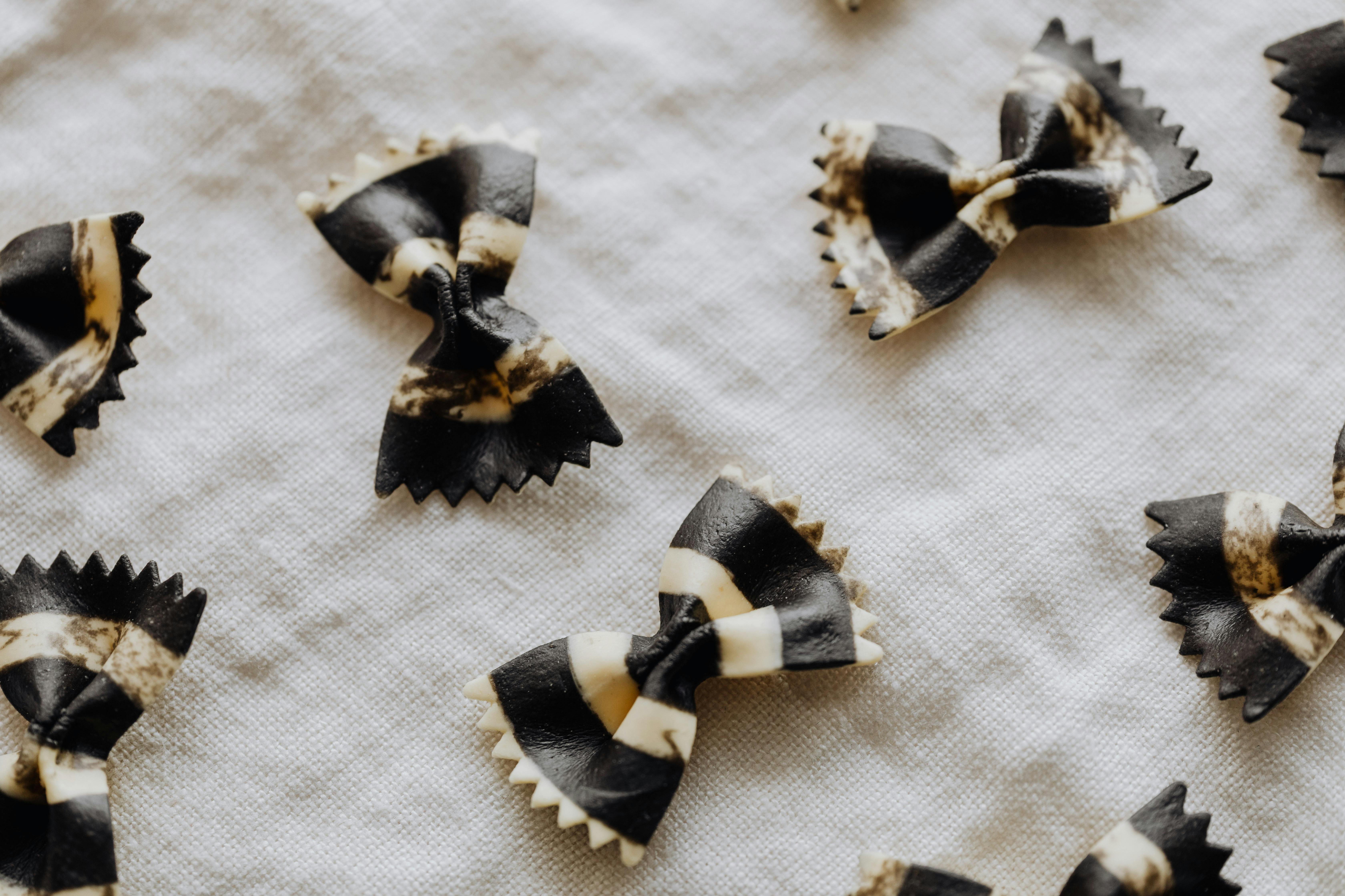 Black and white bow-tie pasta pieces on a white cloth.