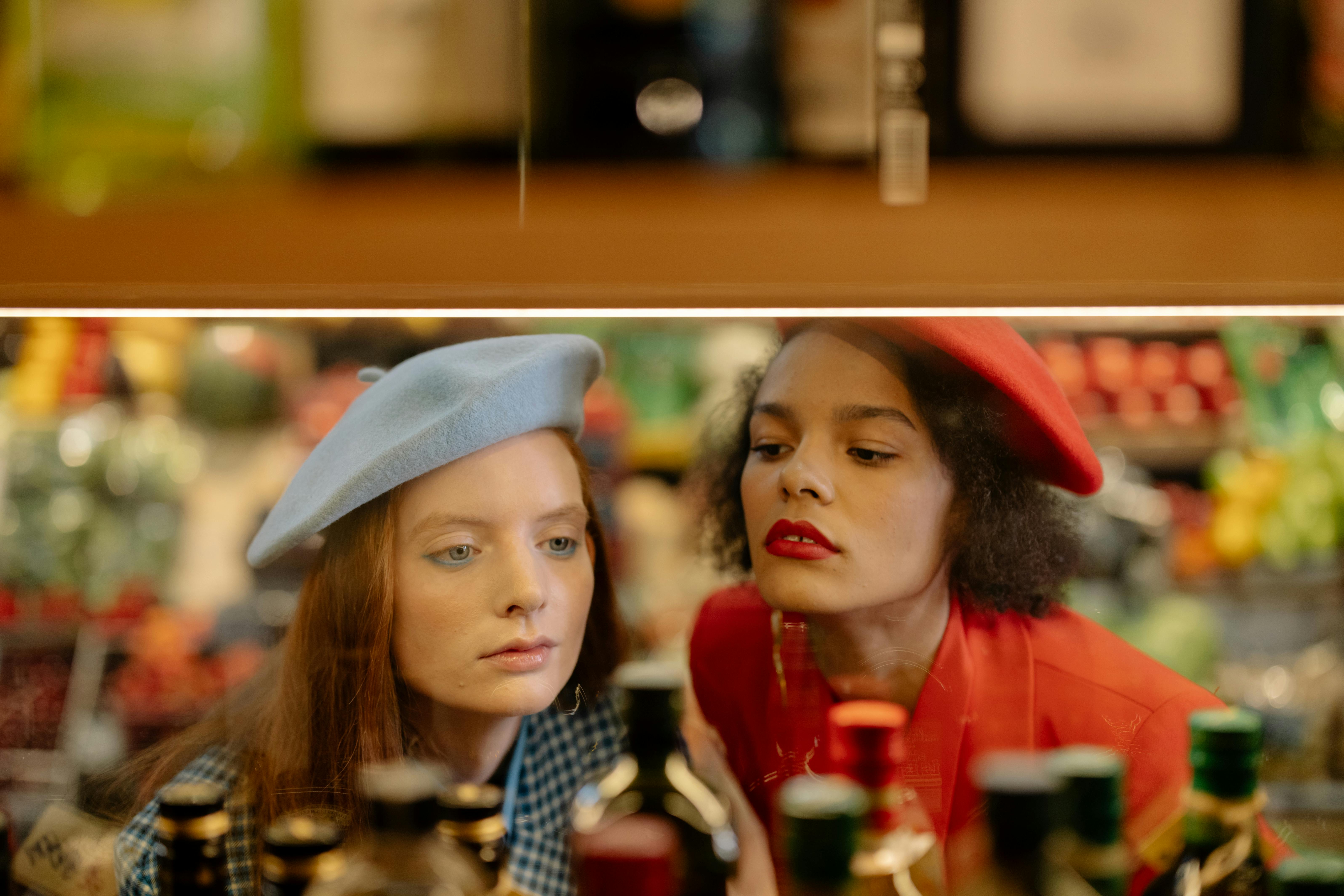 Two people wearing berets look at items behind glass.