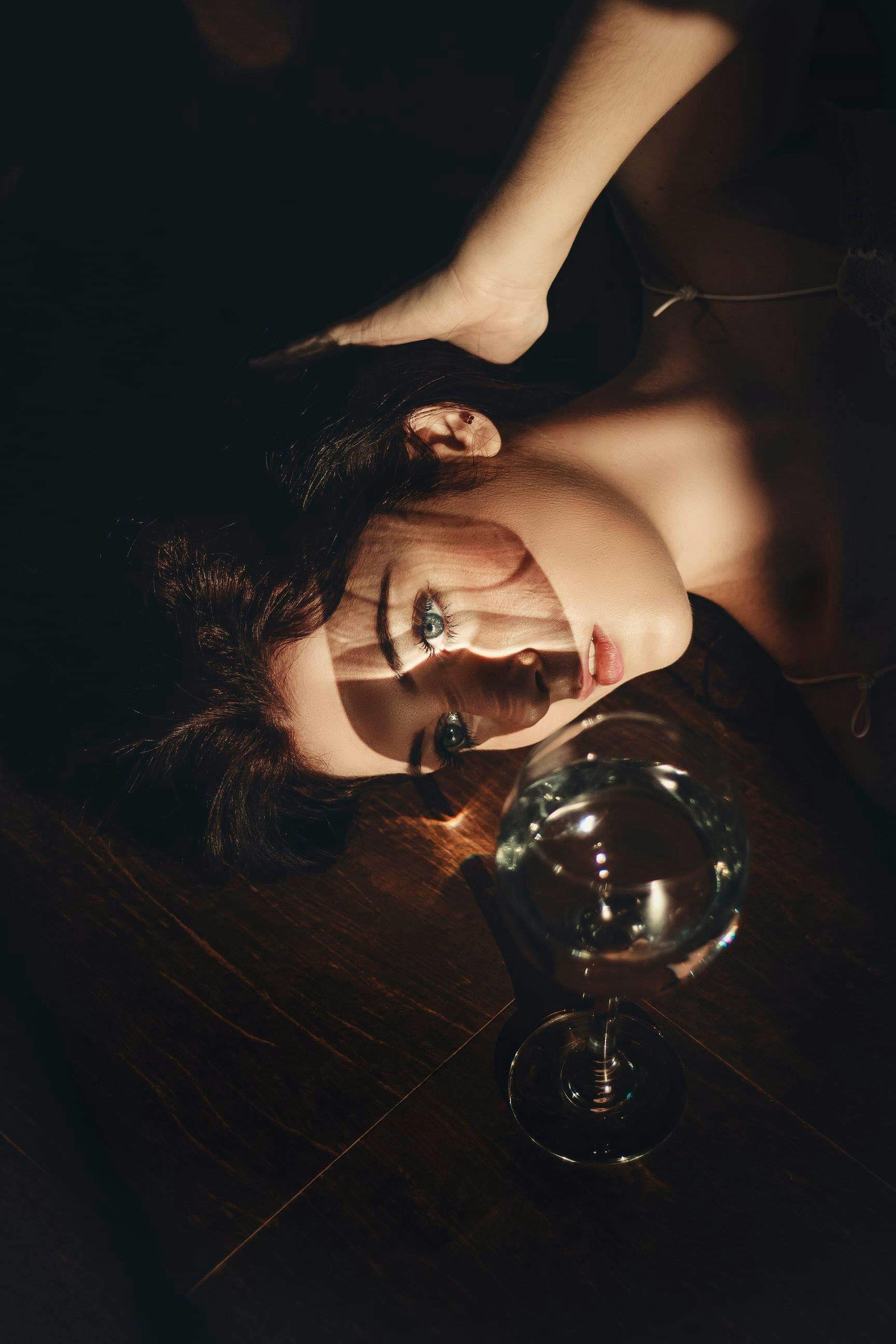 Person lying on floor, dramatic lighting, glass of water nearby.