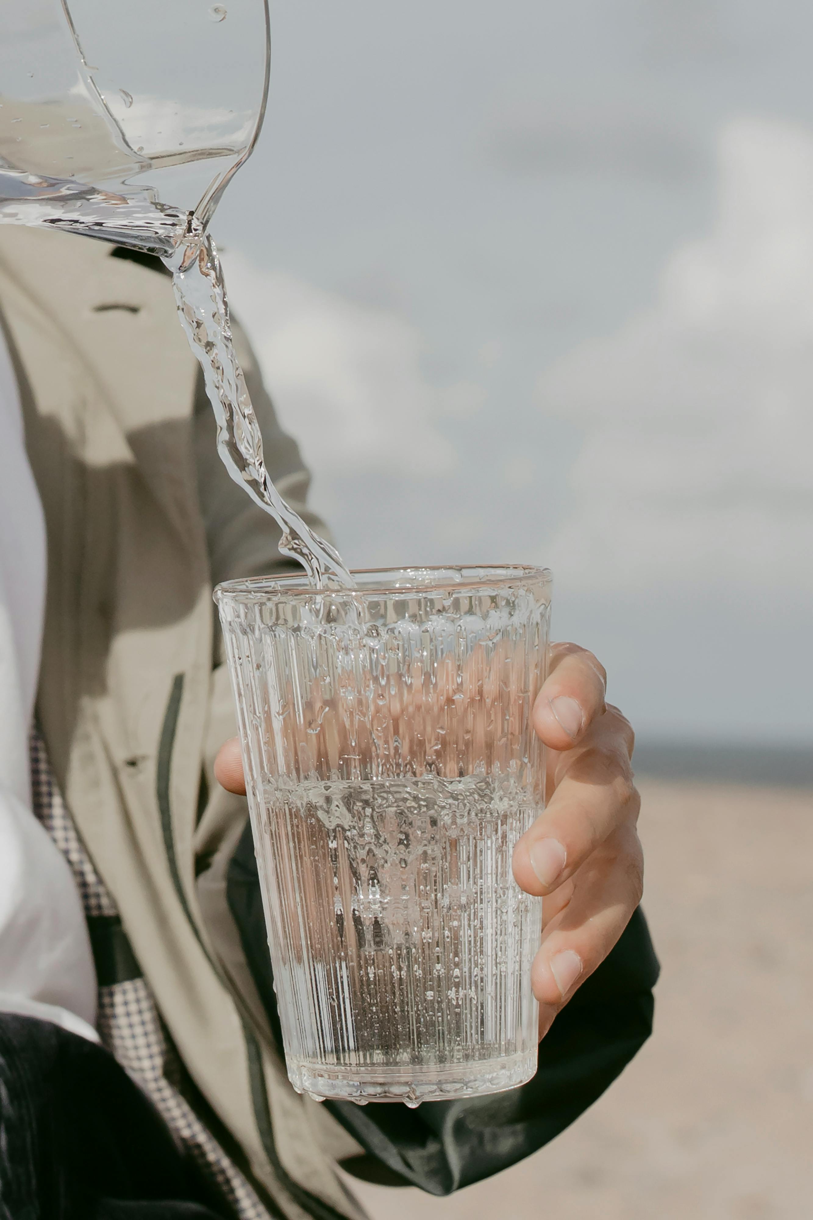 Water being poured into a glass held by a person.
