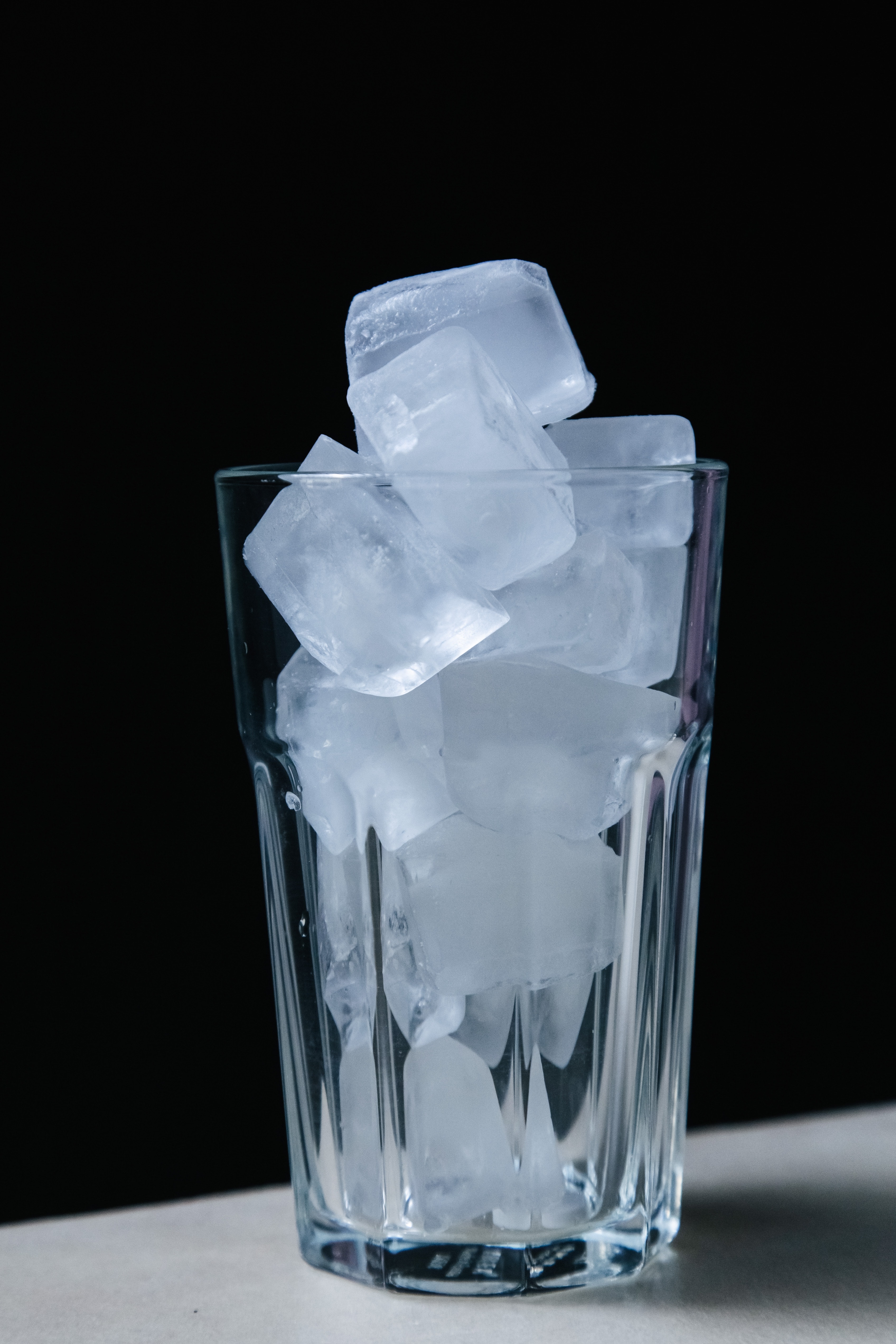 A glass filled with ice cubes against a dark background.