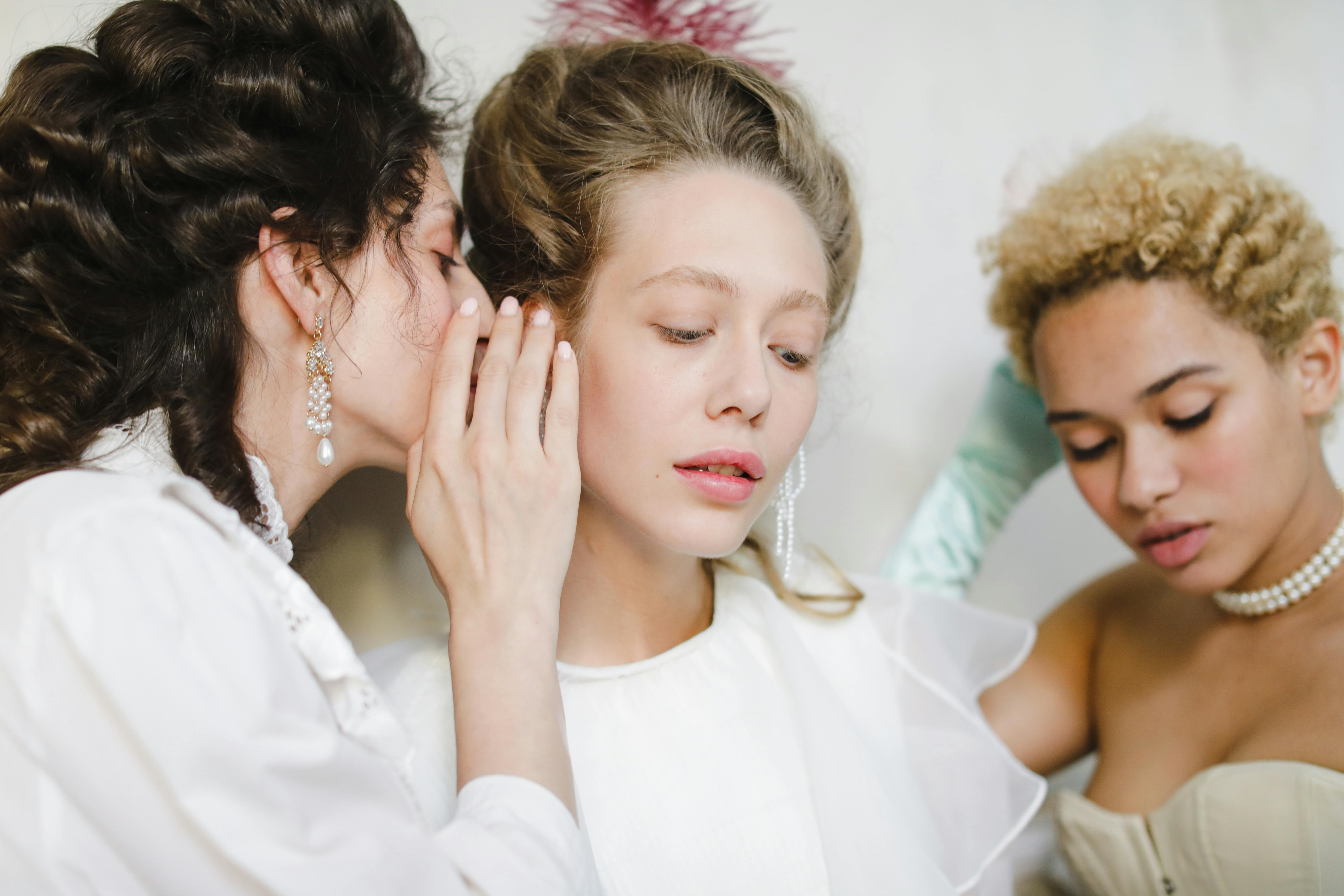Three women in historical attire sharing secrets.