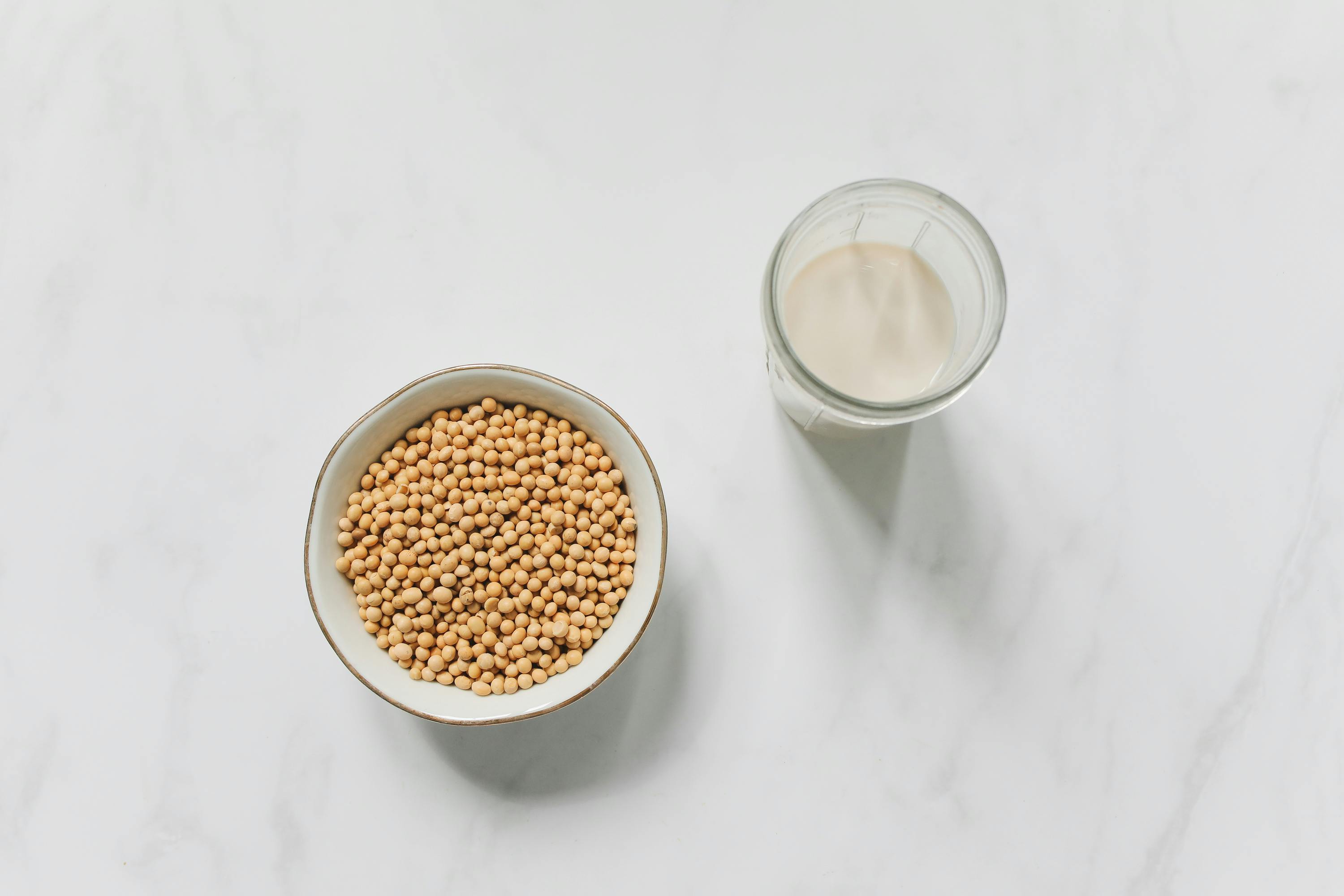 Bowl of soybeans and glass of soy milk on table.