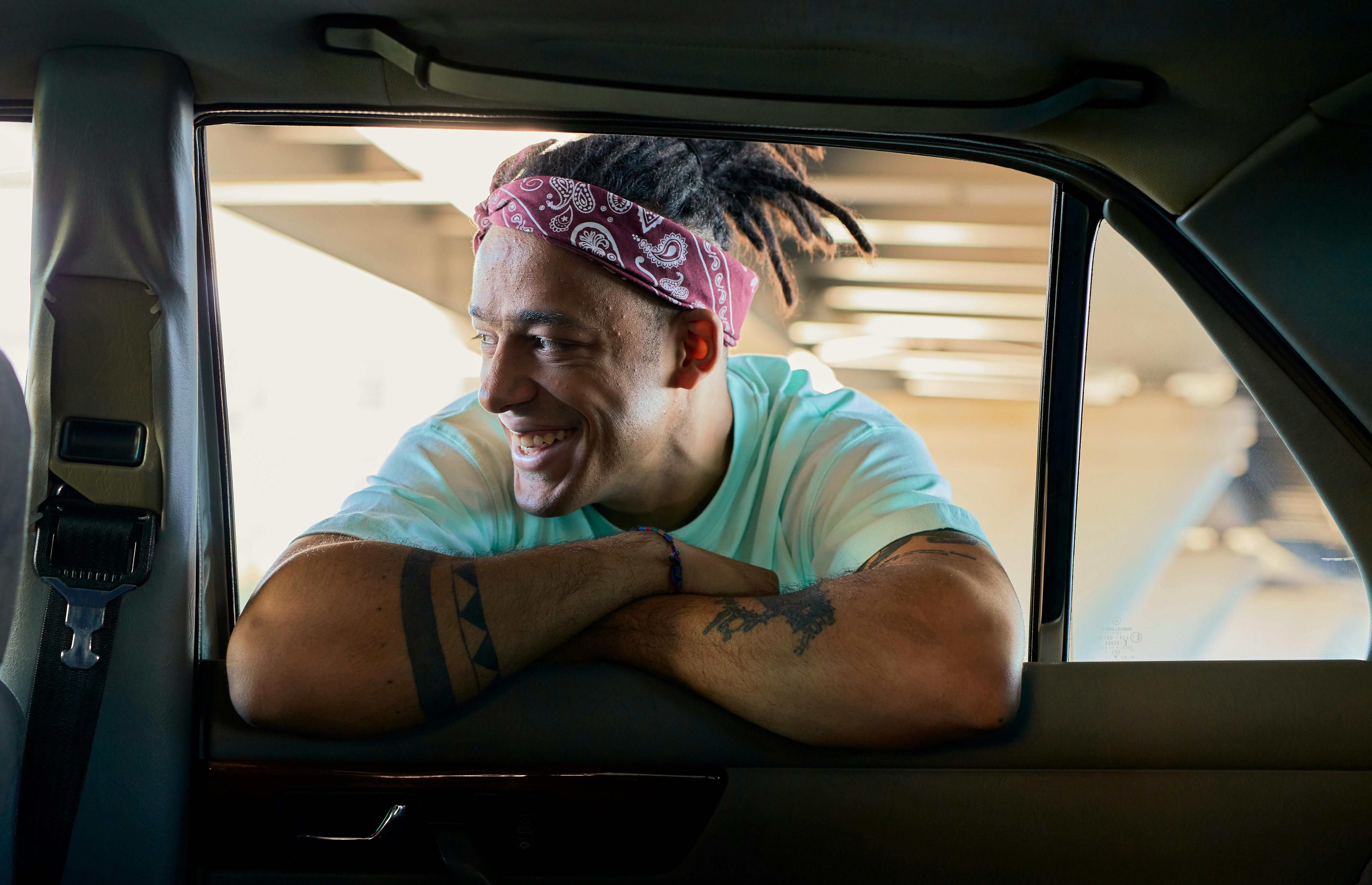 Person smiling and leaning into car window, wearing headband.