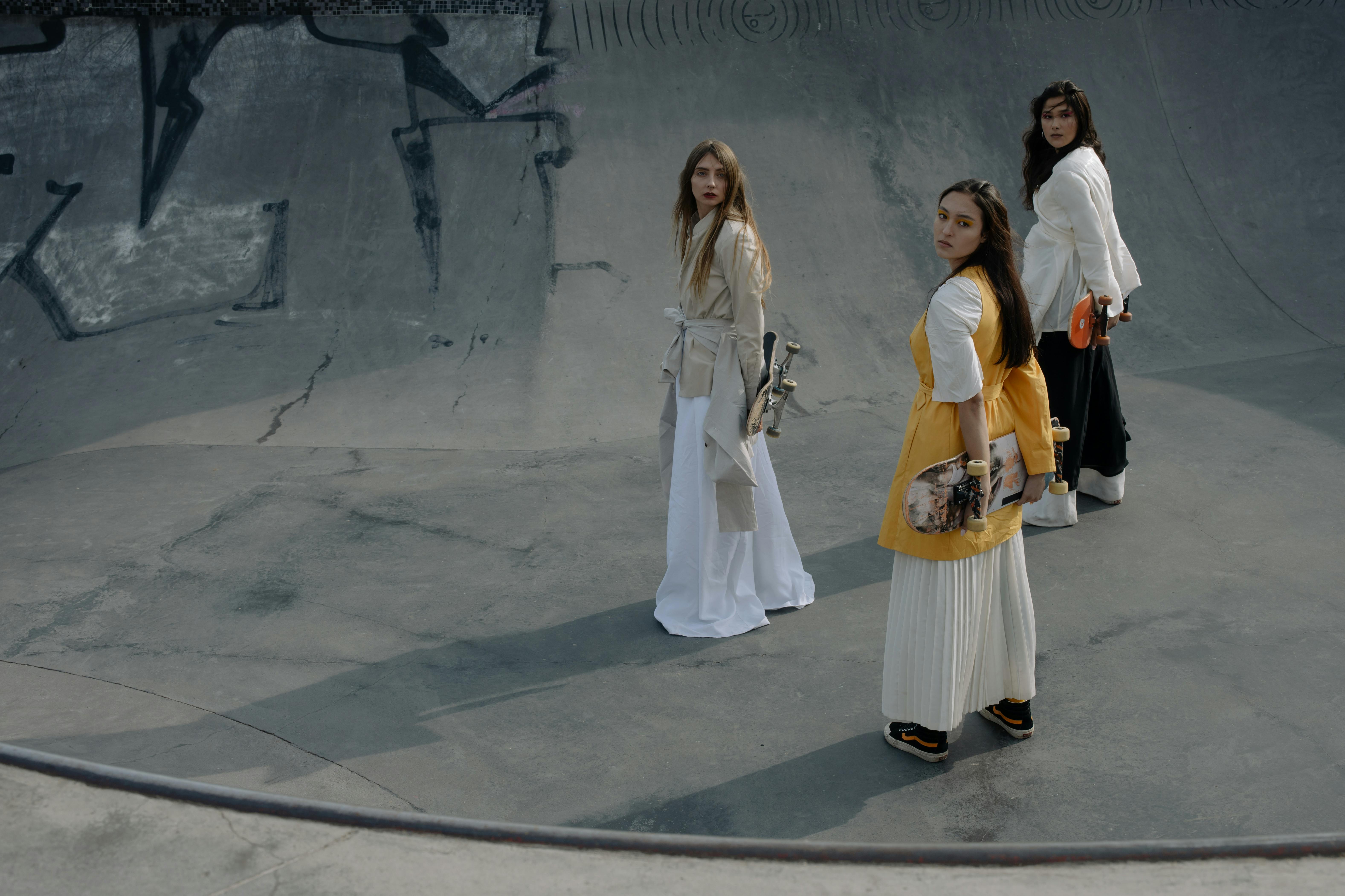 Three people with skateboards in a graffiti-covered skatepark.