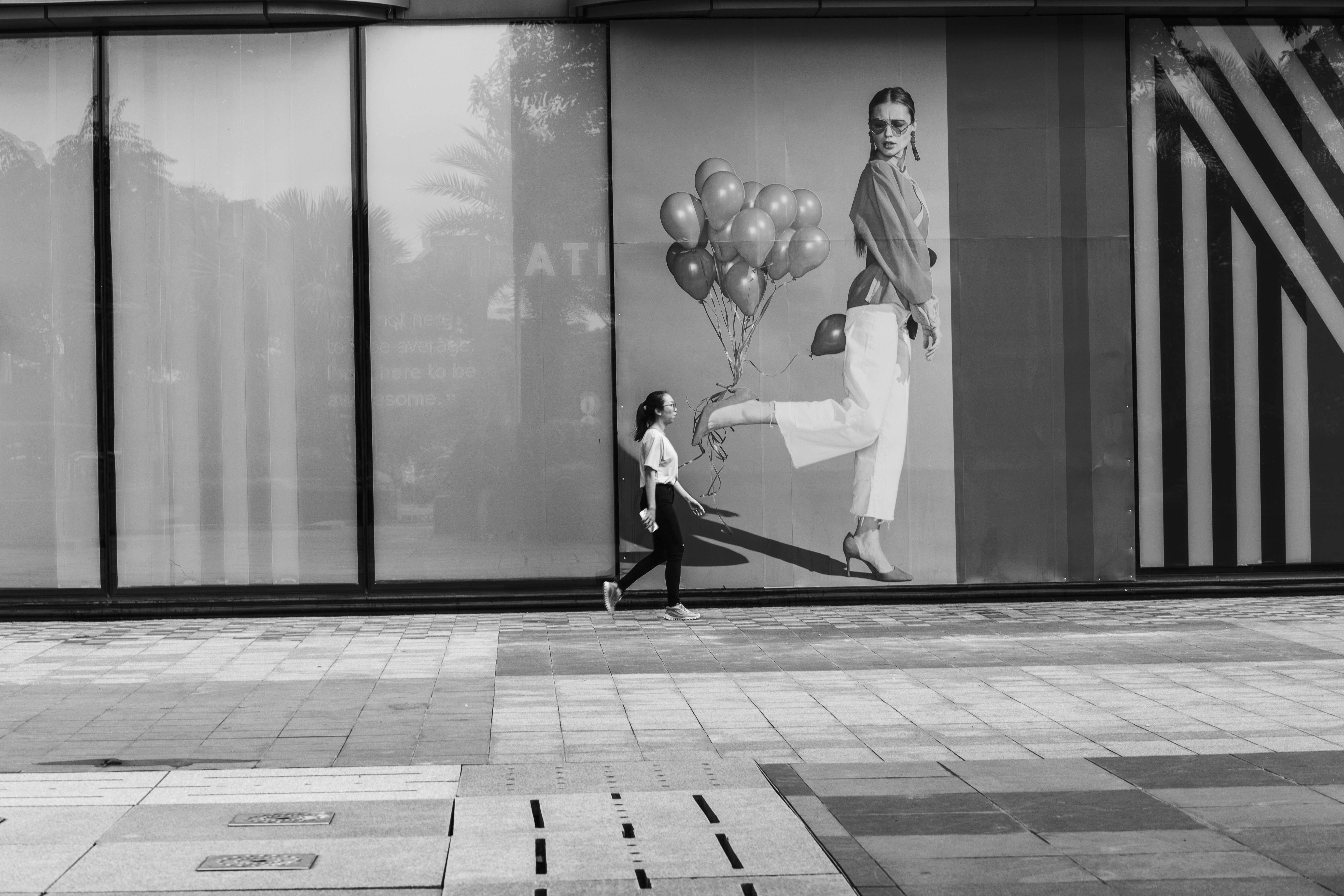 A person walks past a mural of a woman holding balloons.