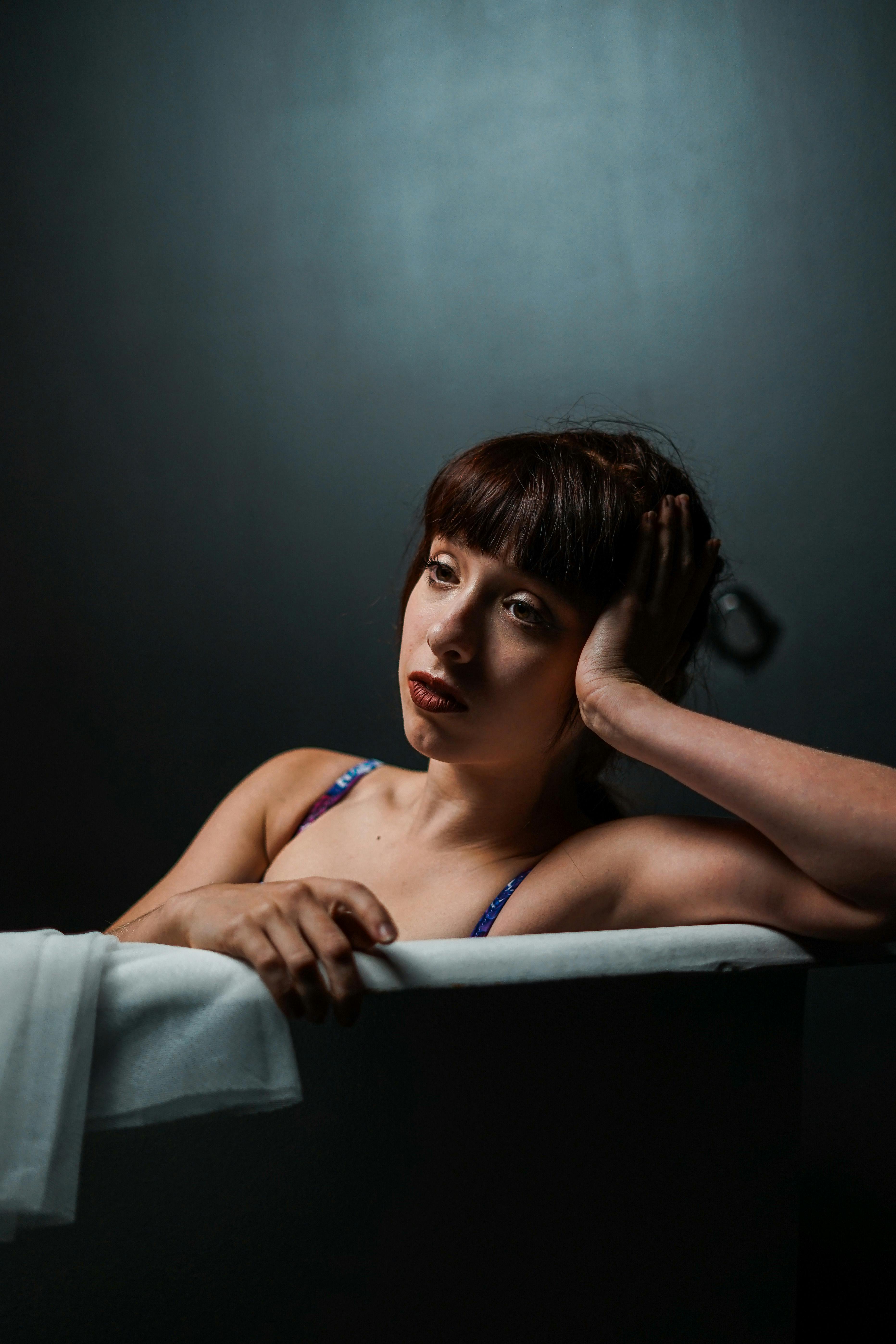 Person sitting in a bathtub, looking thoughtful and relaxed.