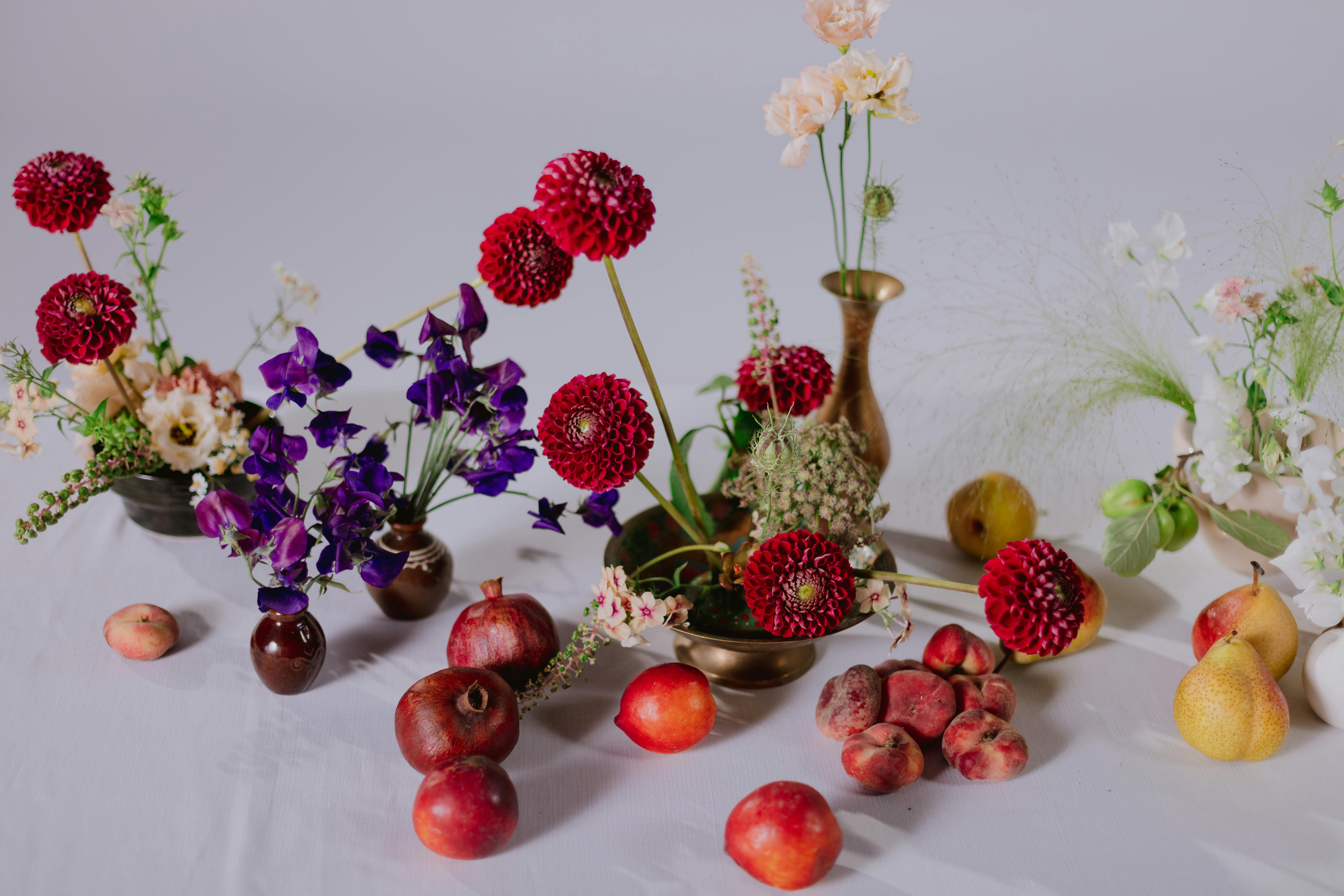 Floral arrangements with dahlias, sweet peas, and fruit.