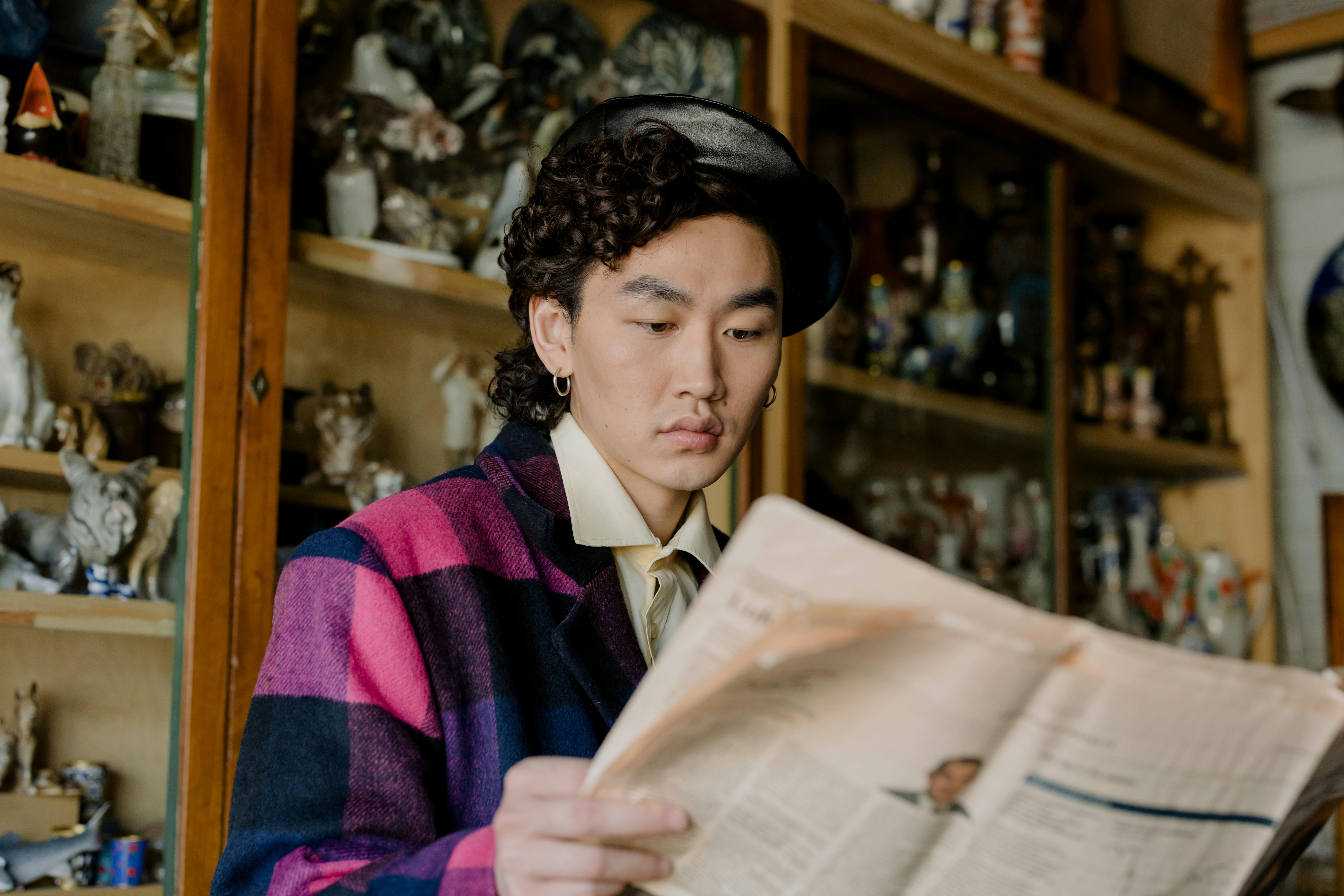 Person in a beret and plaid jacket reading a newspaper.