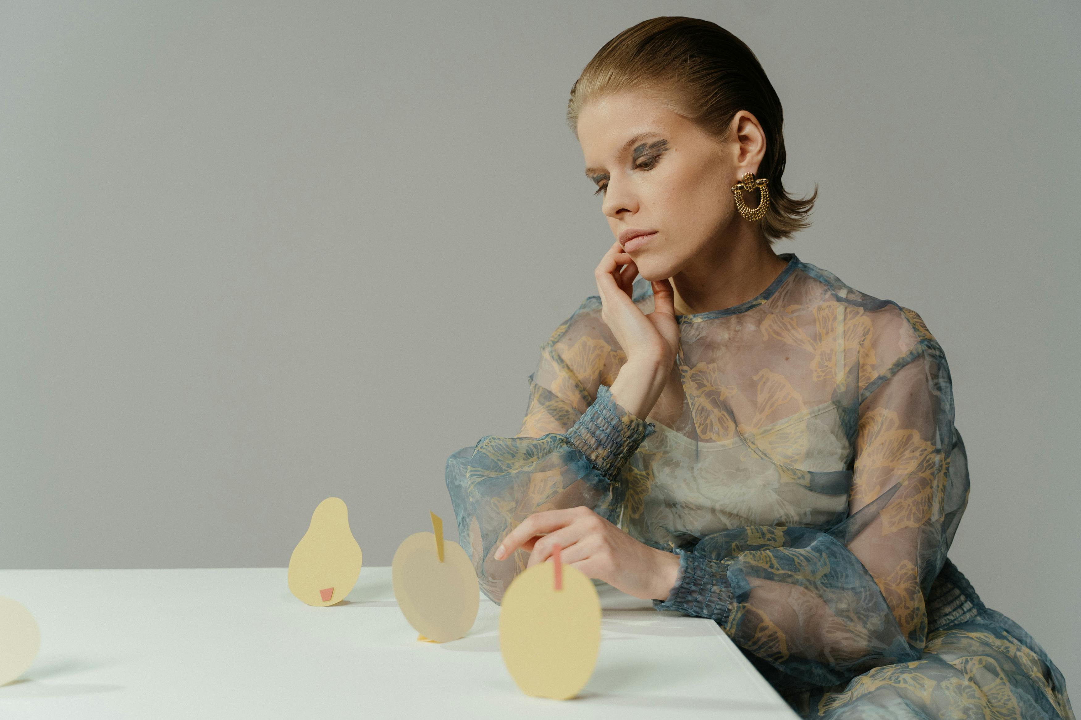 A person sits at a table with paper fruit decorations.