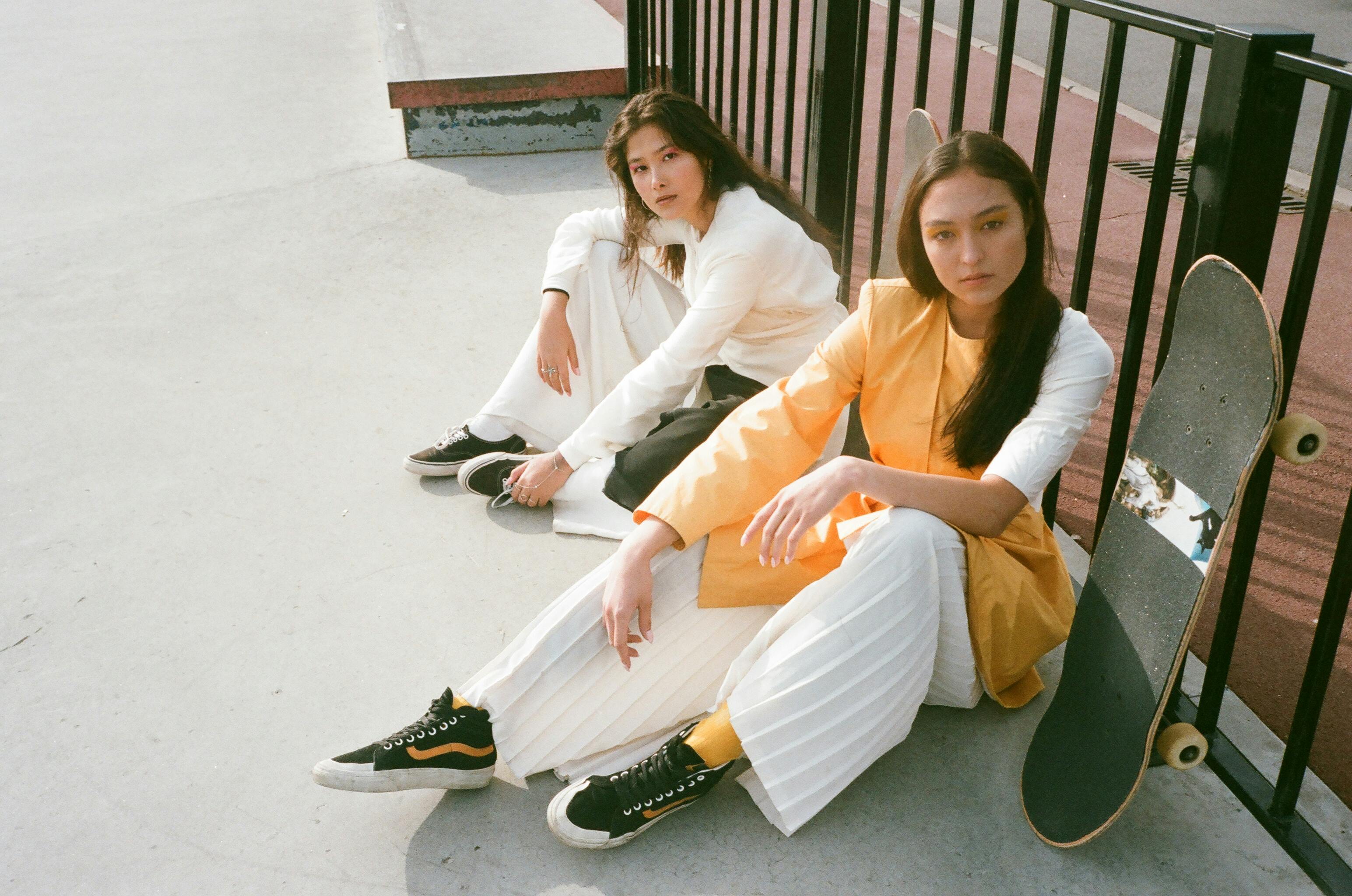 Two people sitting with skateboards at a skatepark.