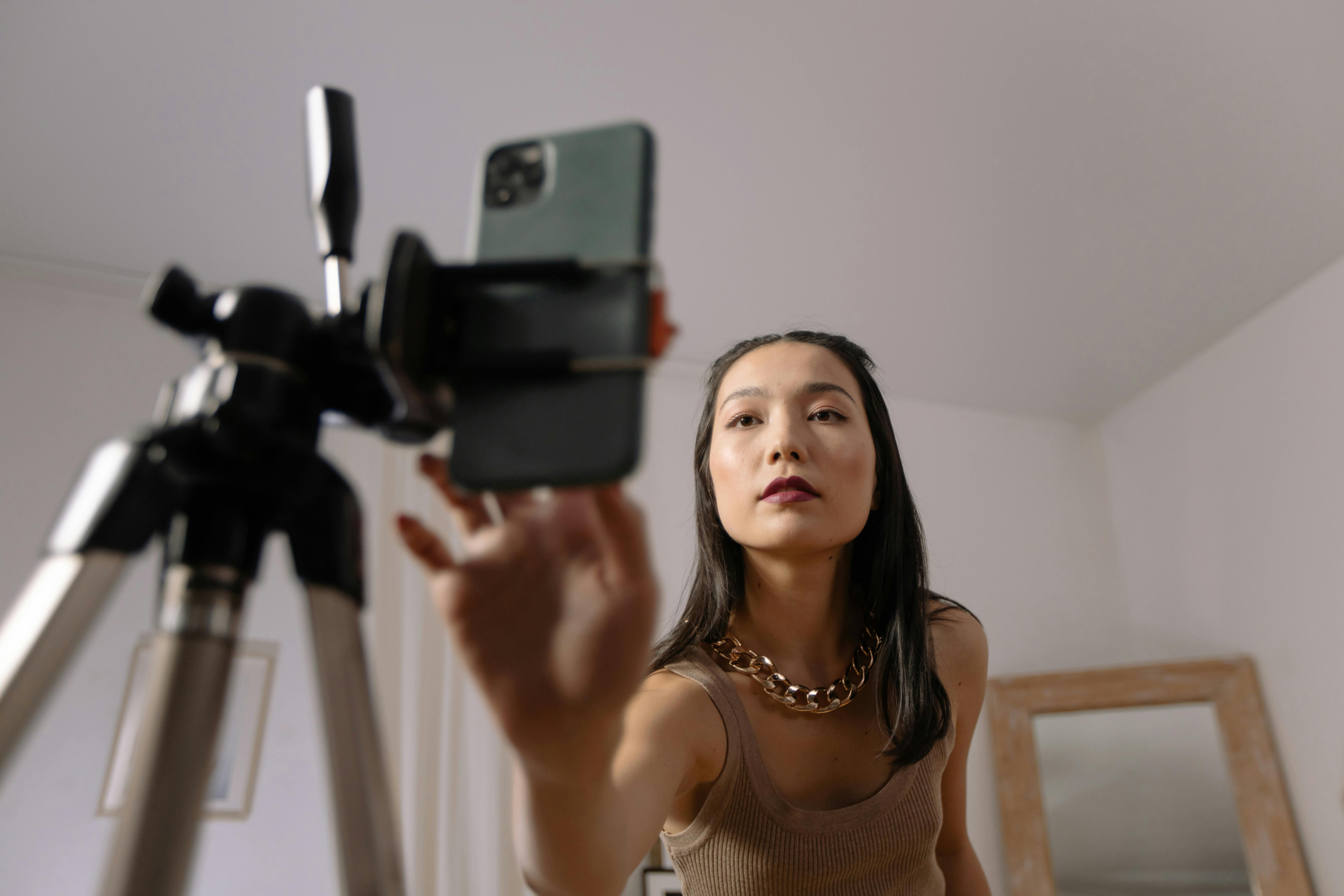 Person adjusting smartphone on tripod, preparing to take photo.