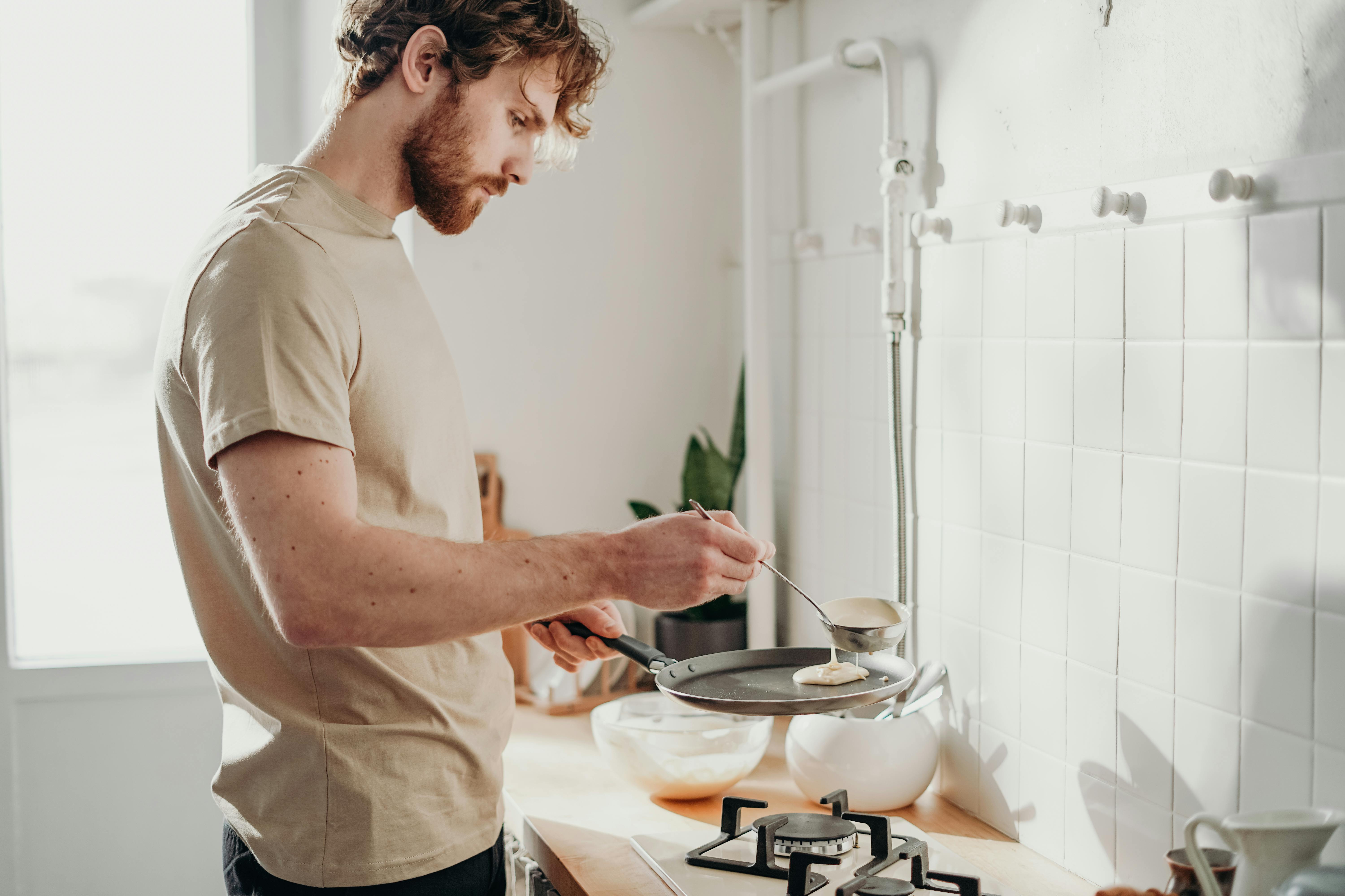 Person making pancakes in a bright, modern kitchen setting.