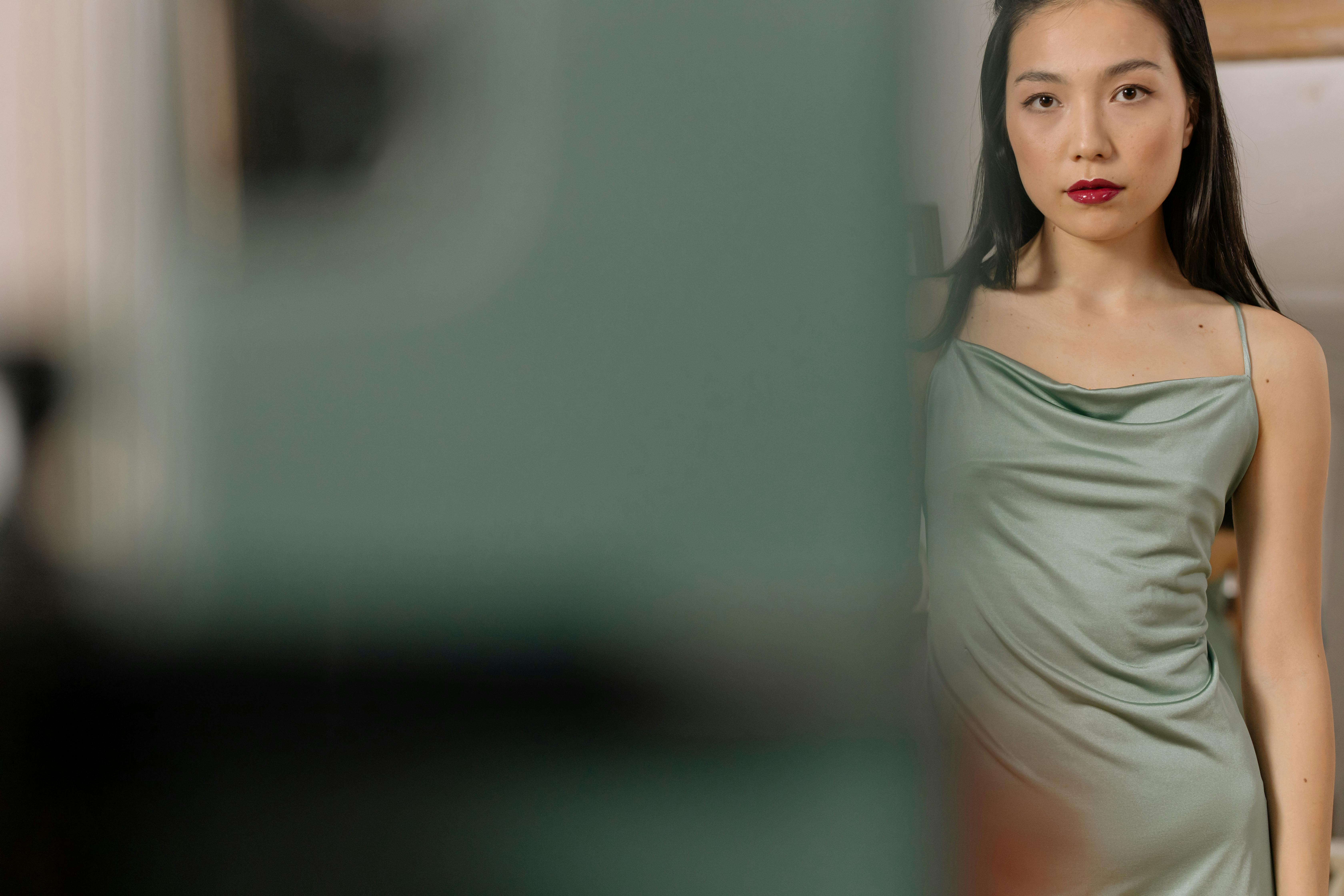Person in green dress partially obscured by a blurred object.
