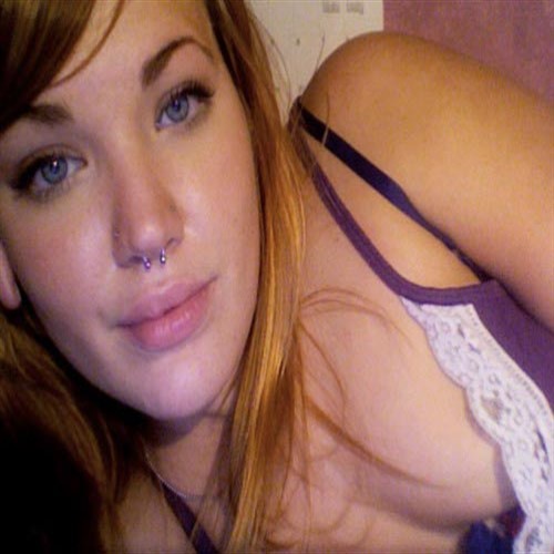 Close-up of a young woman with blue eyes and a septum piercing.
