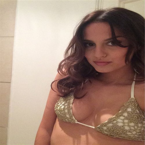 A young woman with long, wavy brown hair wears a gold crochet bikini top.