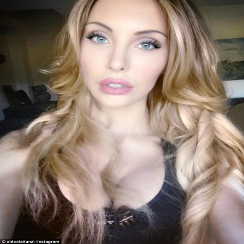 A blonde woman with blue eyes and pink lips takes a selfie.