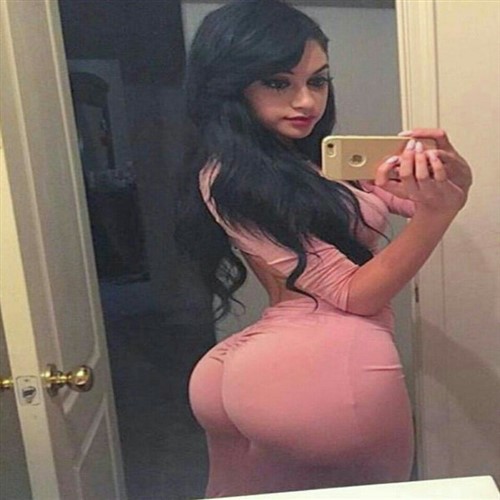 Woman in a pink dress takes a selfie in a mirror.