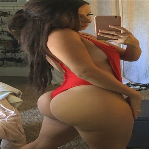 Woman in red one-piece swimsuit taking a mirror selfie.