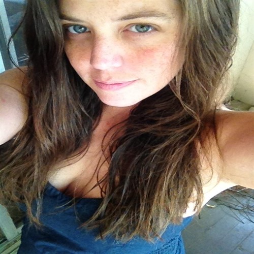 A young woman with long brown hair and blue eyes smiles at the camera.